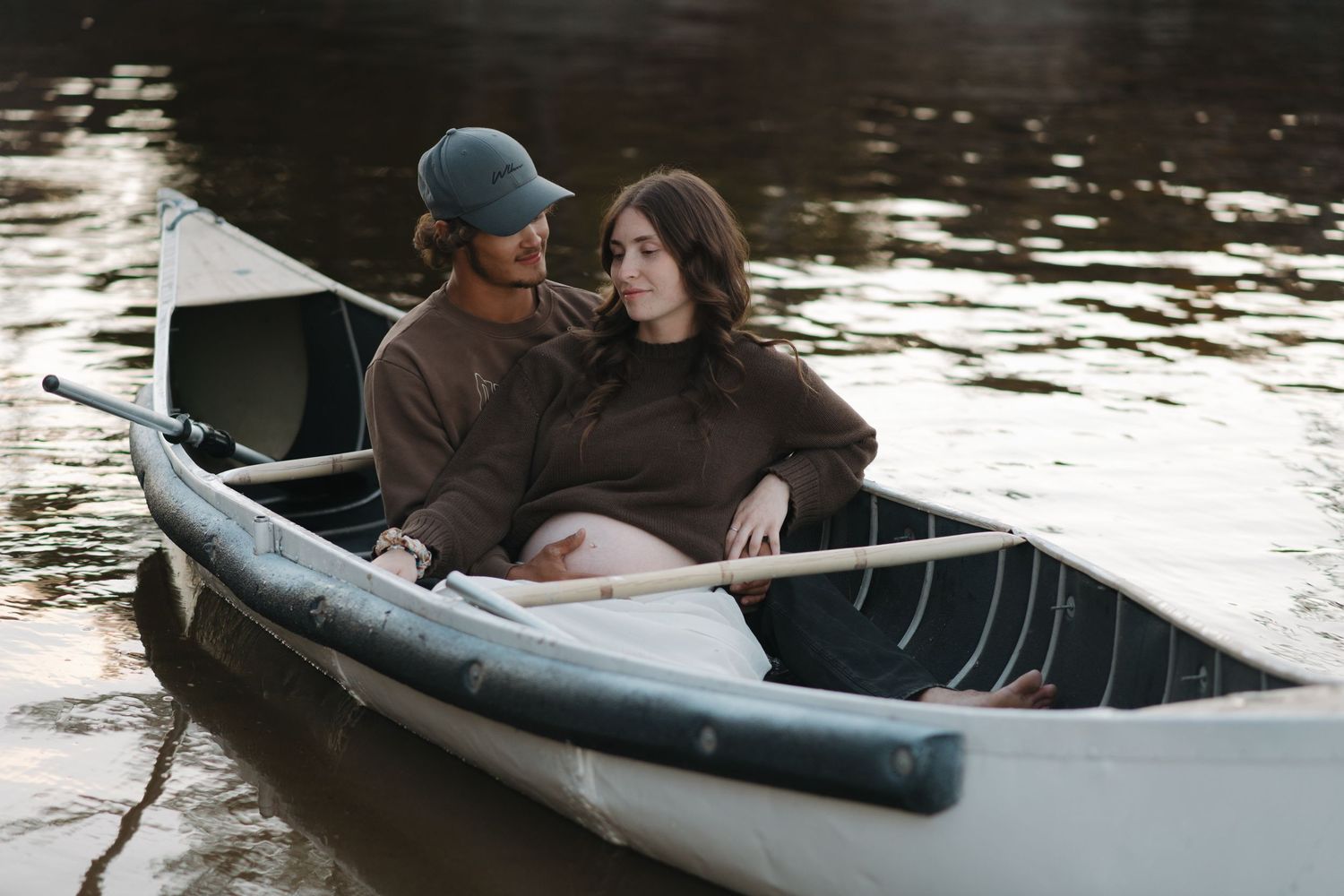 Couple sharing an intimate moment in a canoe on a tranquil lake.