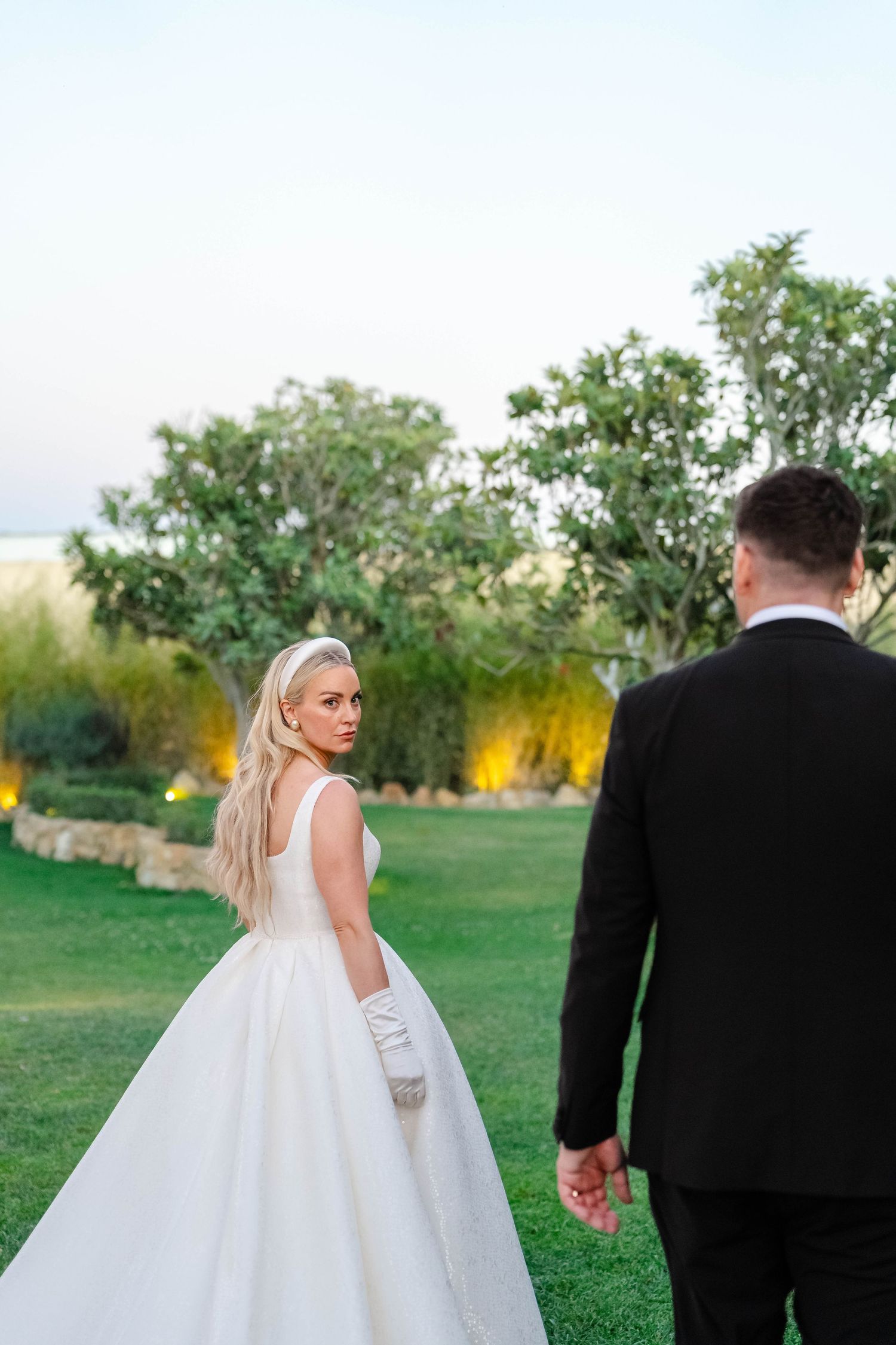 Elegant outdoor wedding photo with couple against garden backdrop.
