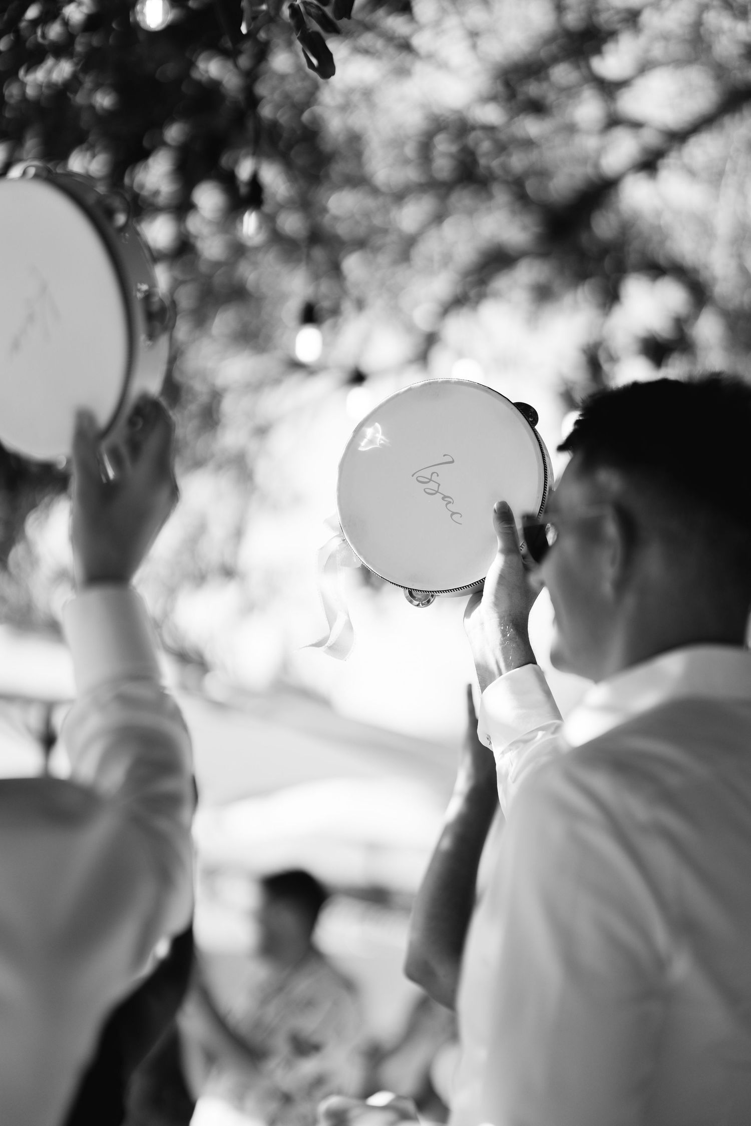 Blurred black and white image of people dancing at a wedding reception with bokeh lighting effects in background.