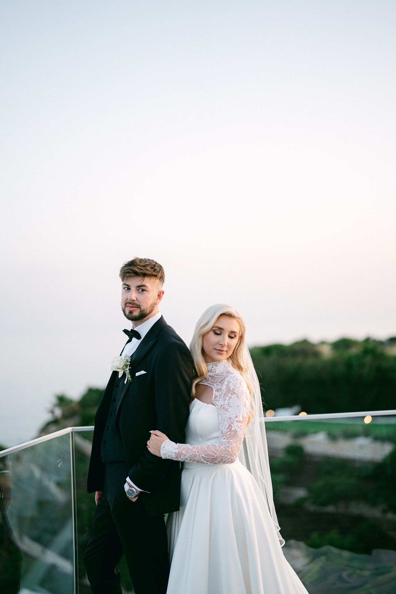 Modern wedding photography showcases stylish couple against minimalist outdoor backdrop.