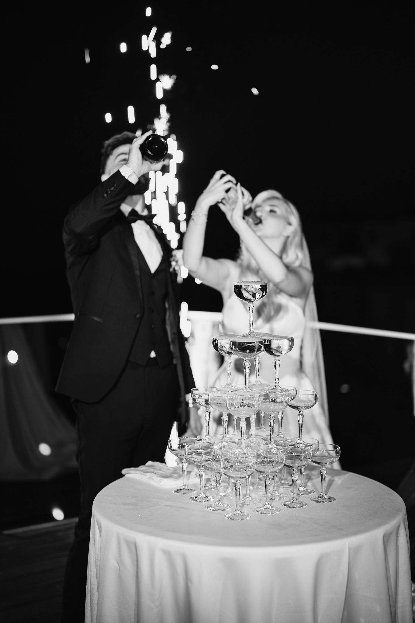 Wedding couple pouring champagne into a tower of glasses at their reception.