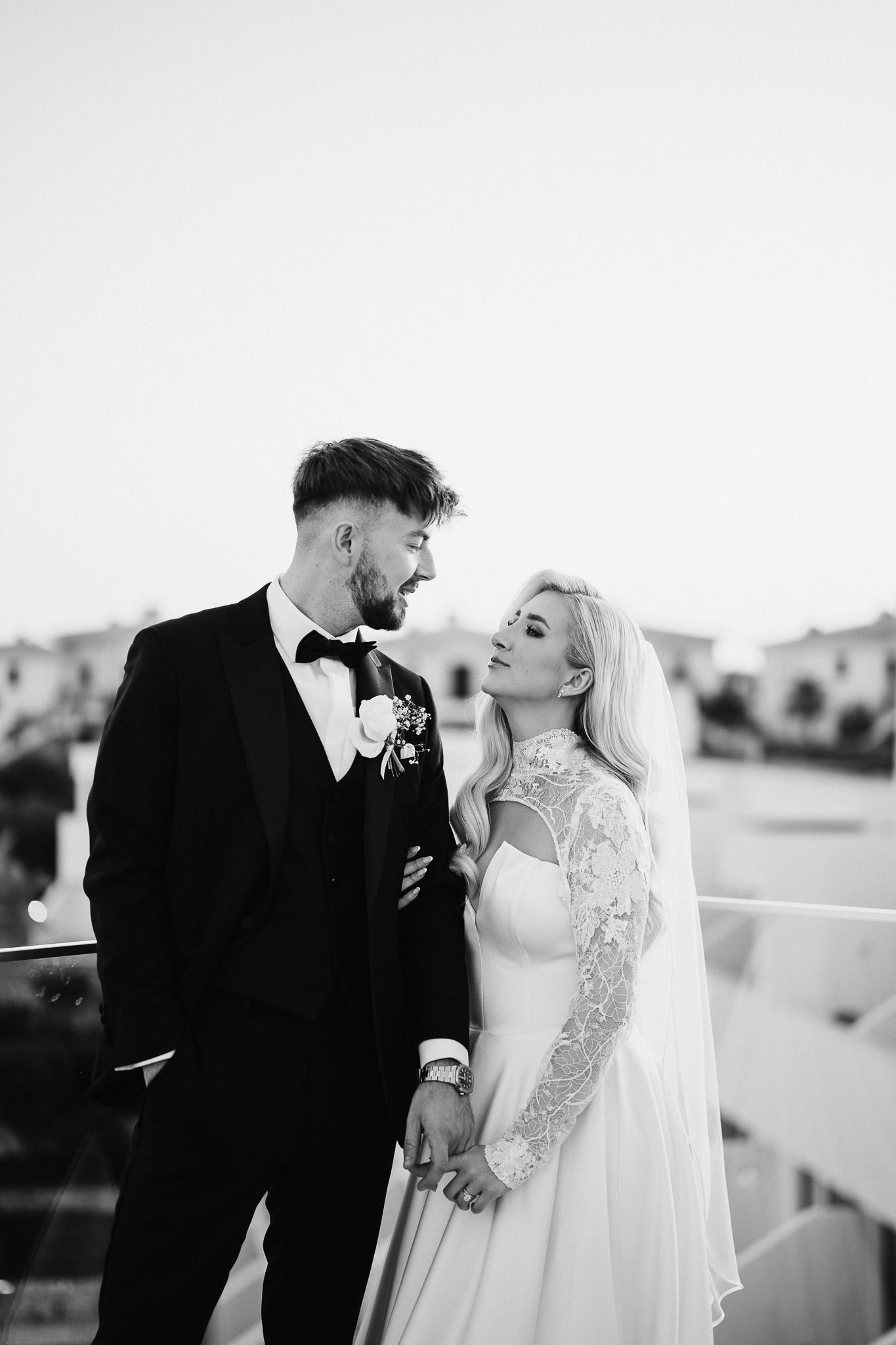 Black and white portrait of newlyweds in elegant attire sharing tender moment.