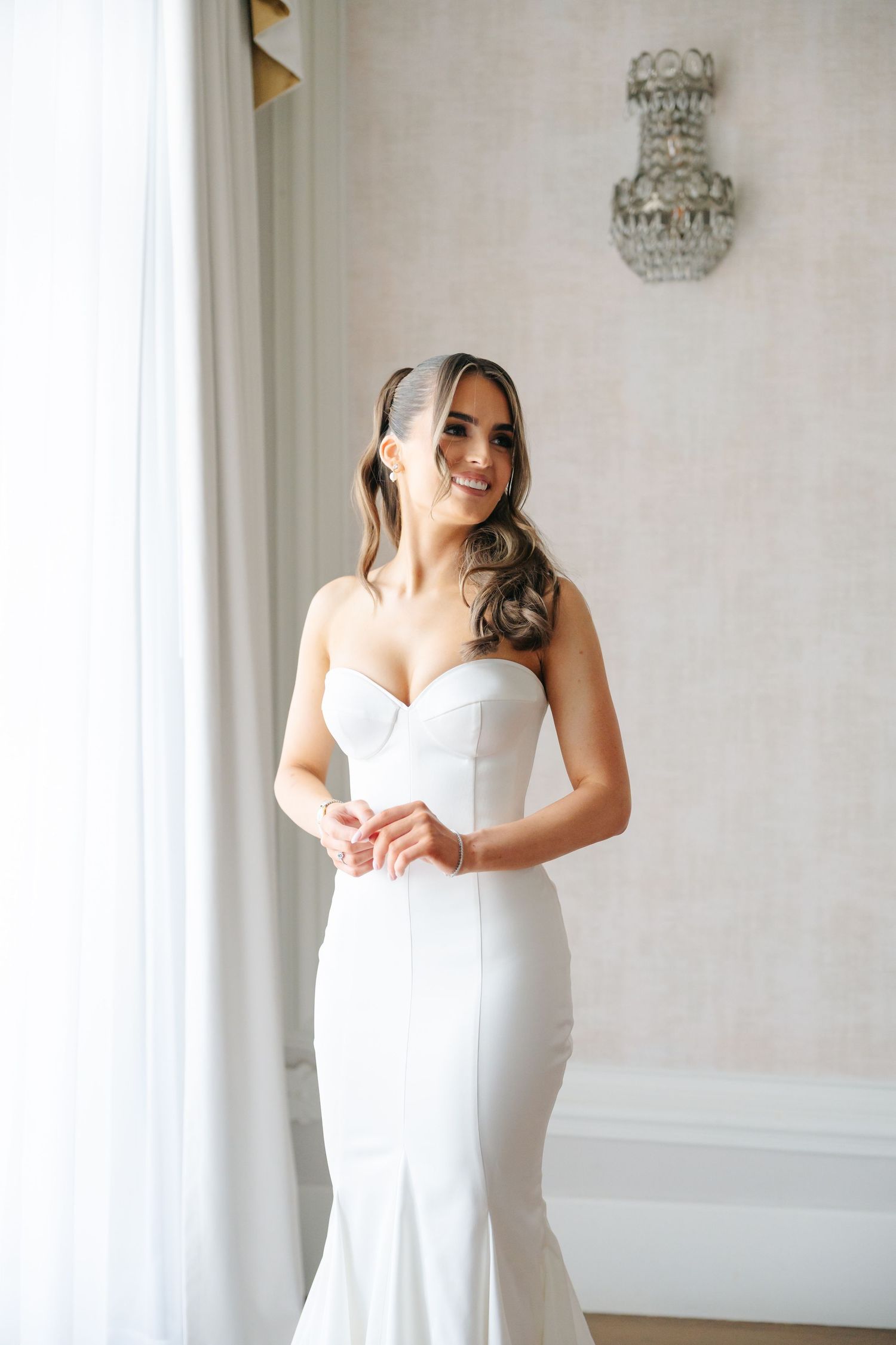 Elegant white wedding dress photographed in natural window light.