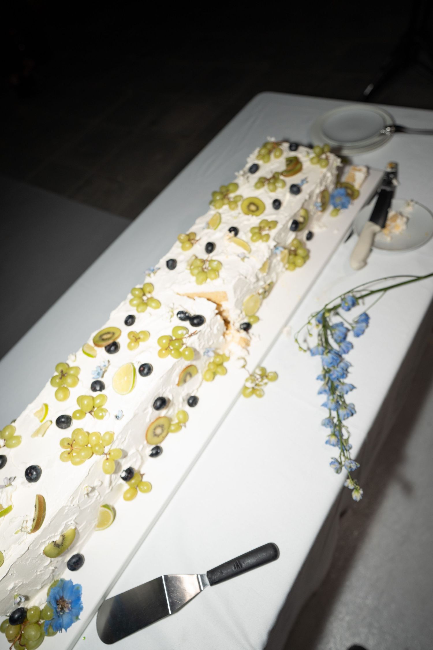 Close-up of an artistic white wedding cake decorated with yellow and blue floral details.
