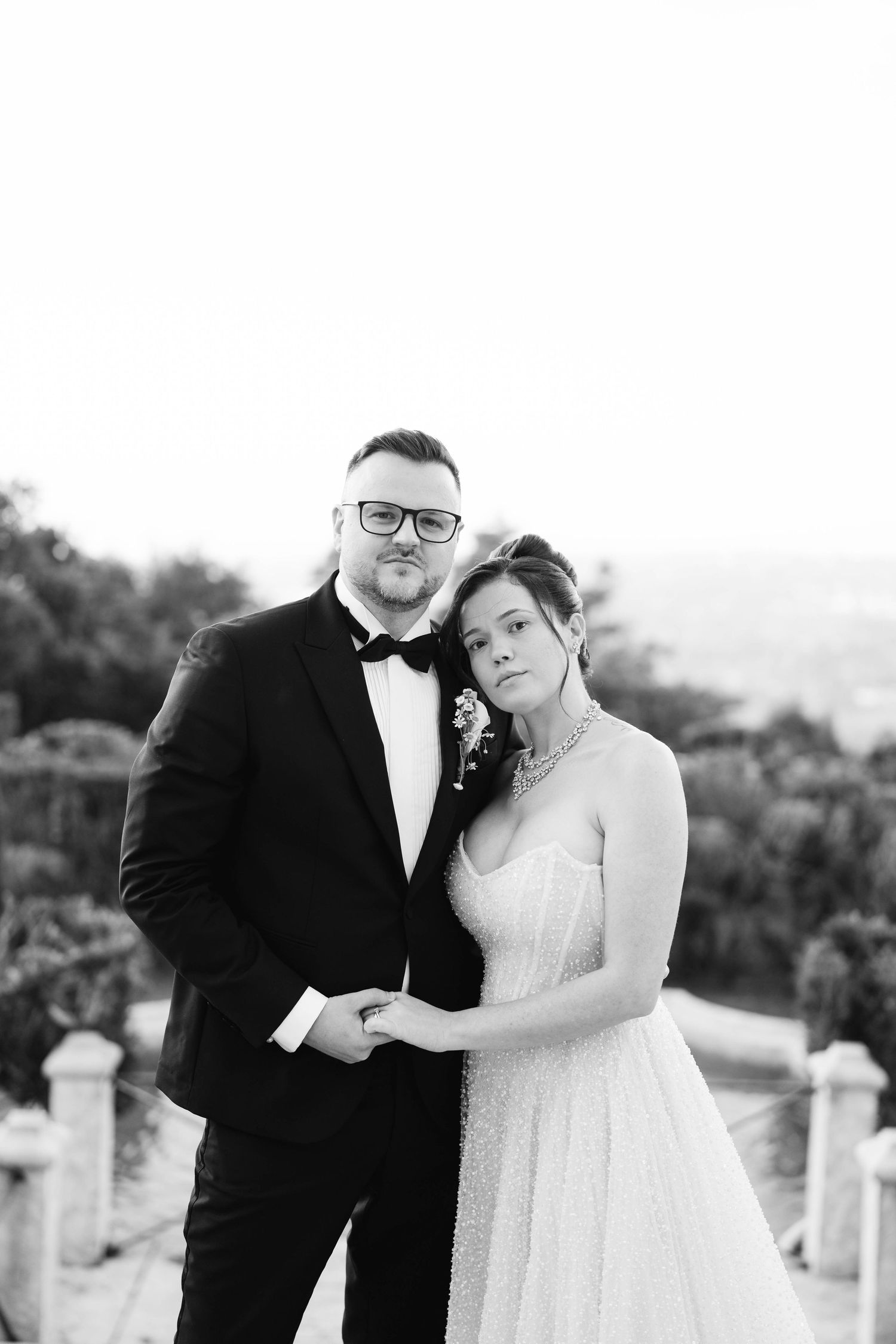 A romantic black and white wedding photo series showing tender moments between a couple in formal attire outdoors.