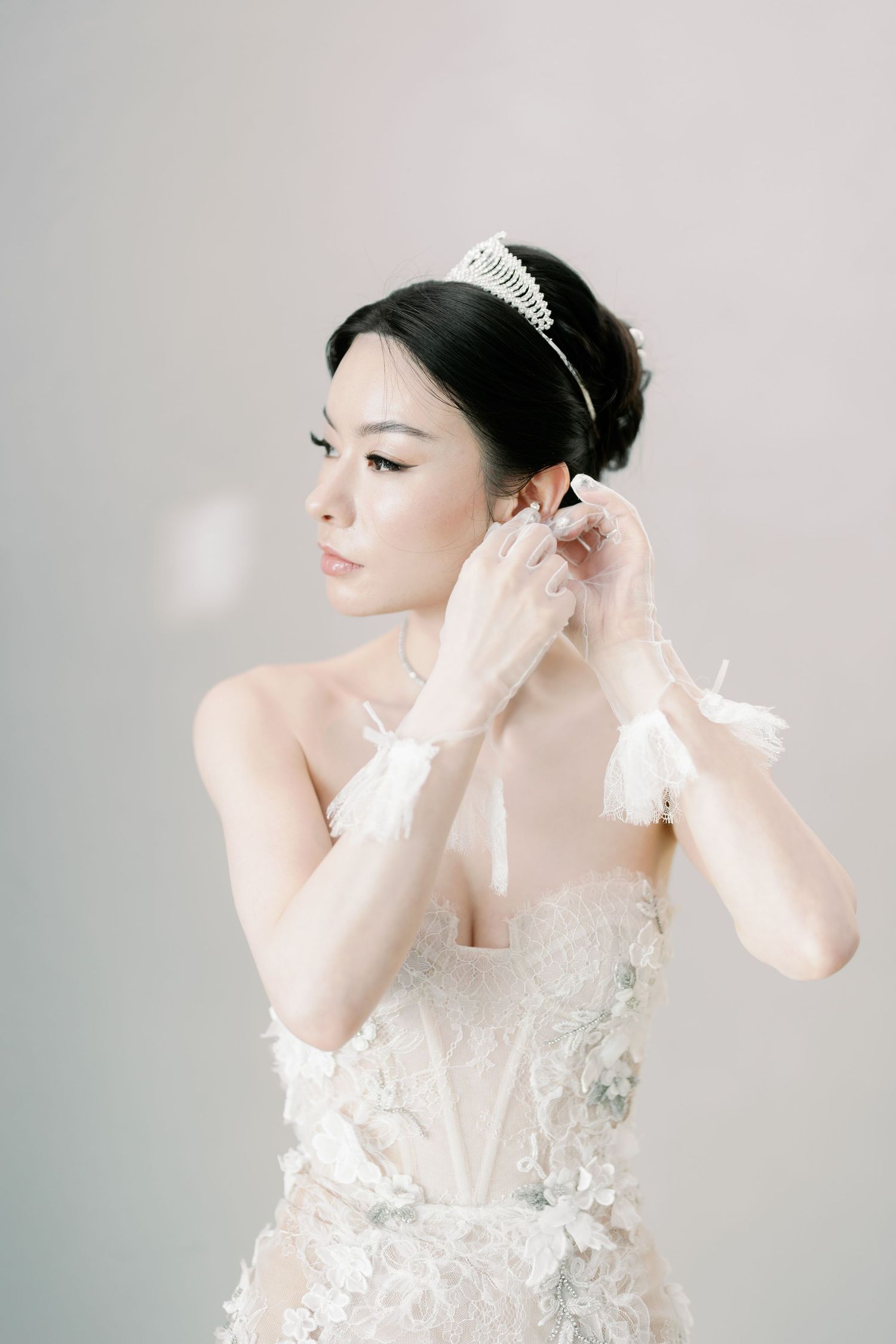Elegant bridal portrait showcasing a detailed white wedding dress and classic accessories.