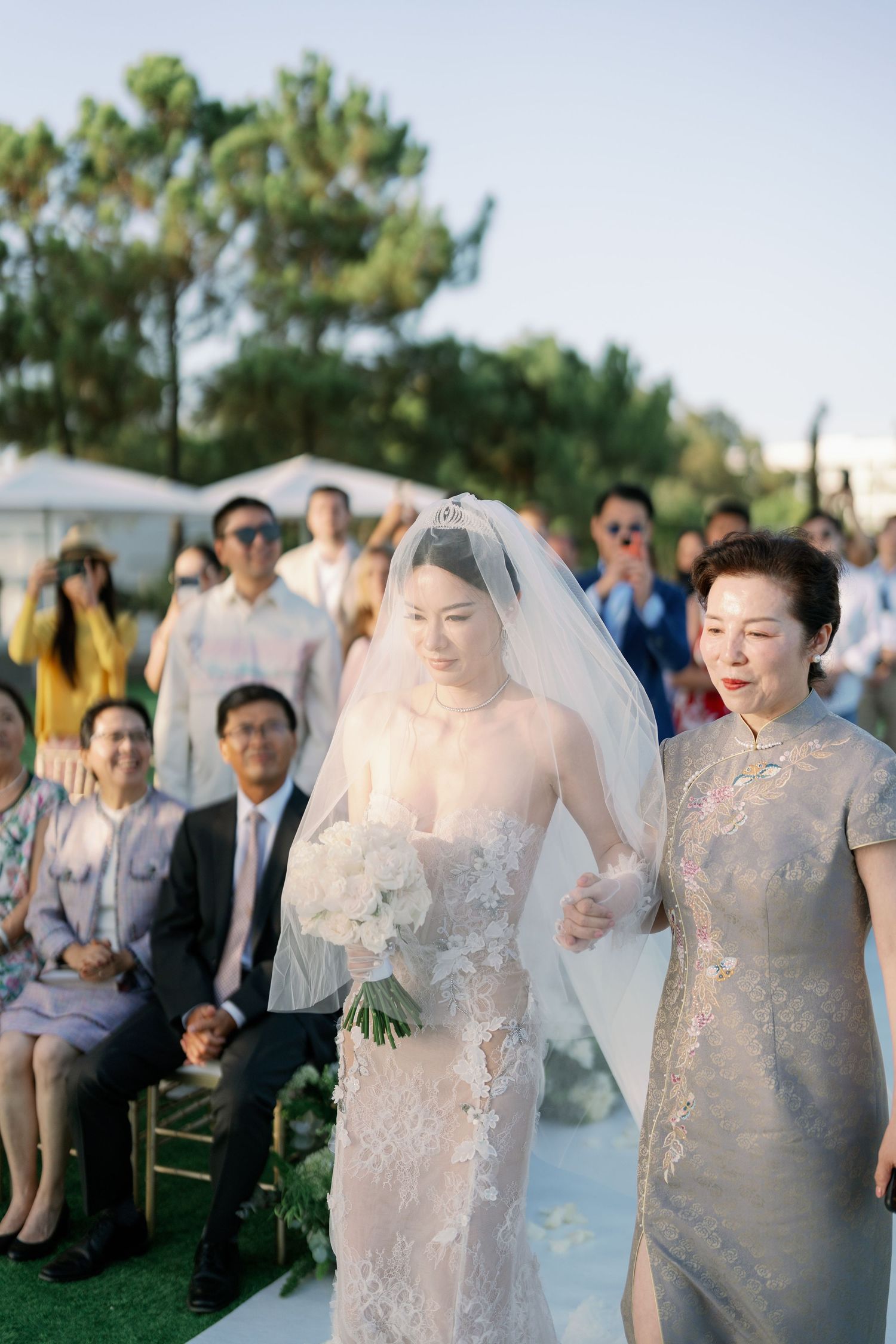 Wedding processional on white aisle runner with floral decorations in garden setting.