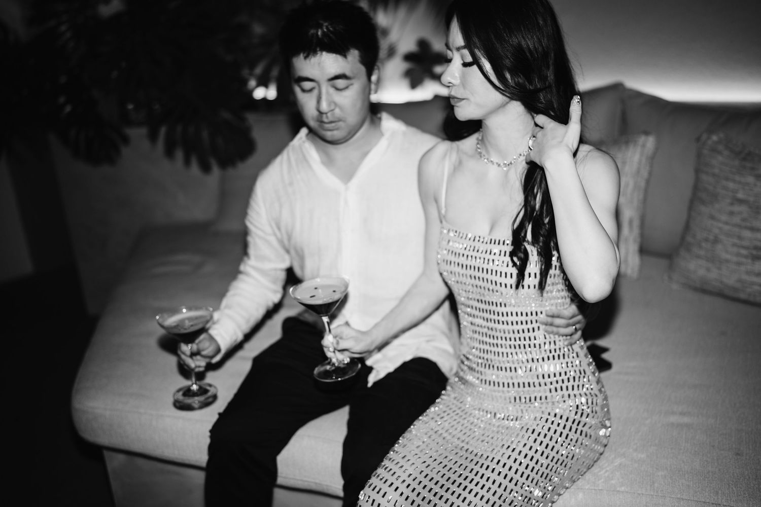 Couple relaxing on couch with drinks during evening celebration.