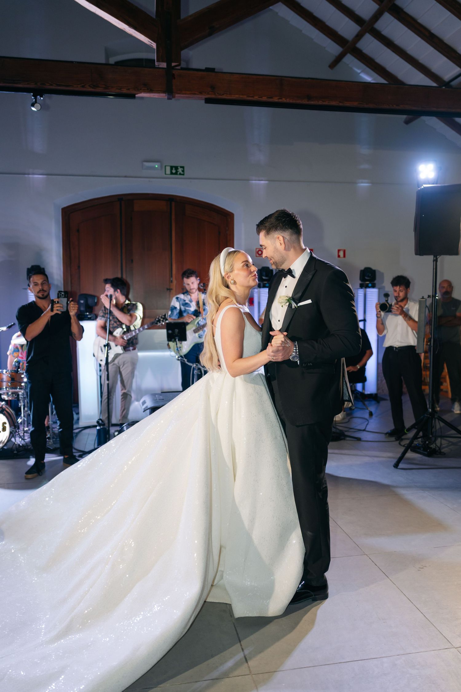 Wedding couple dances in spacious reception hall with flowing white dress.