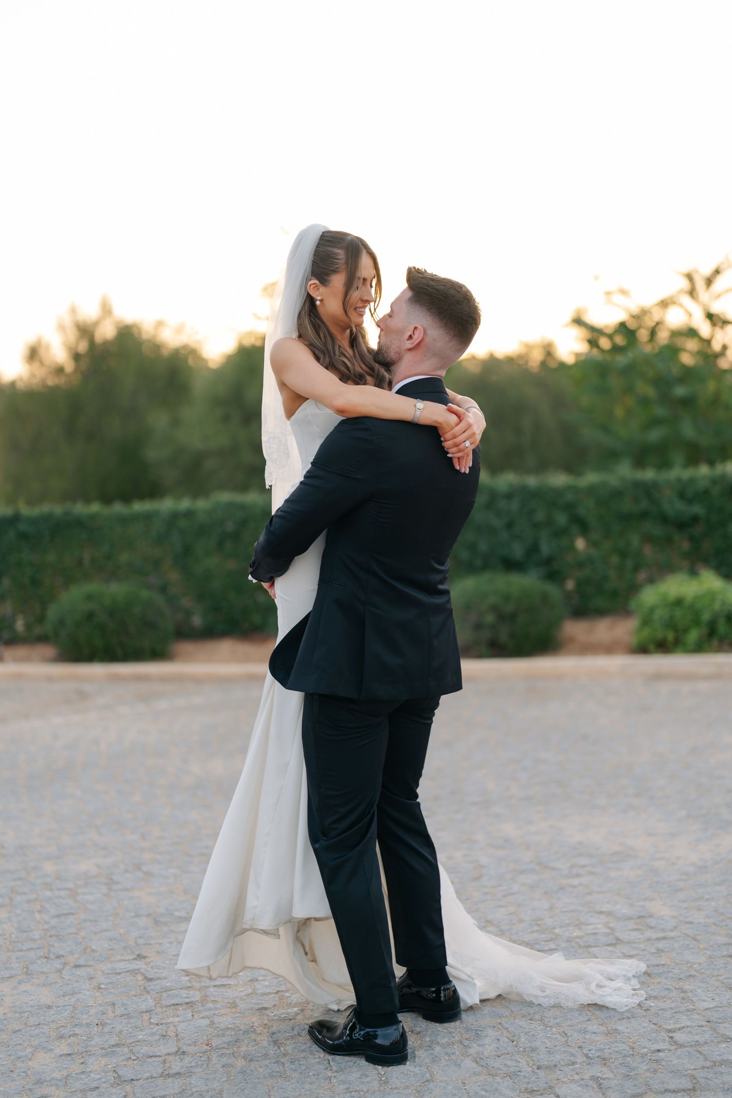 A groom lifts his bride in a romantic embrace on their wedding day.