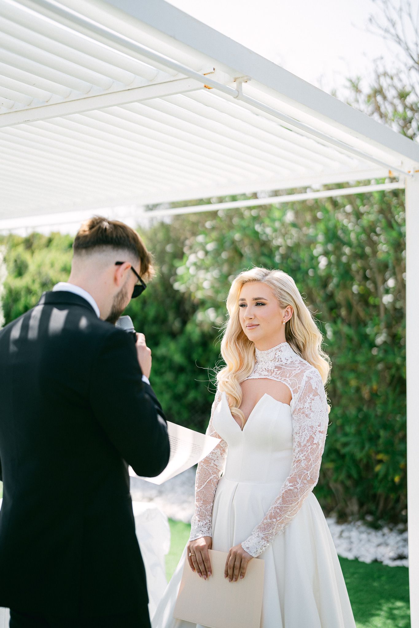 Emotional first look between couple under white pergola during wedding ceremony.