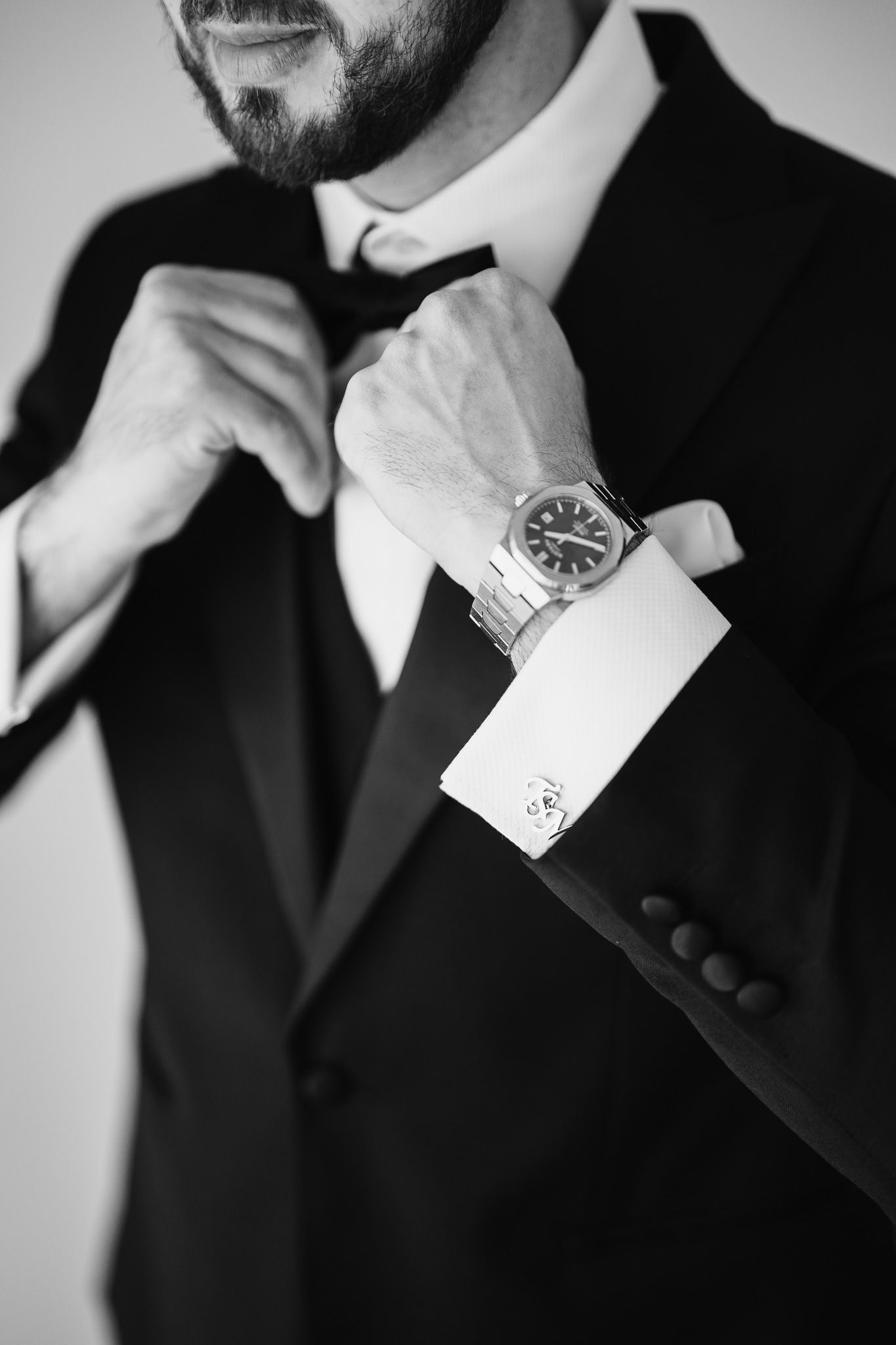 Close-up details of formal attire with bow ties and watches in black and white.