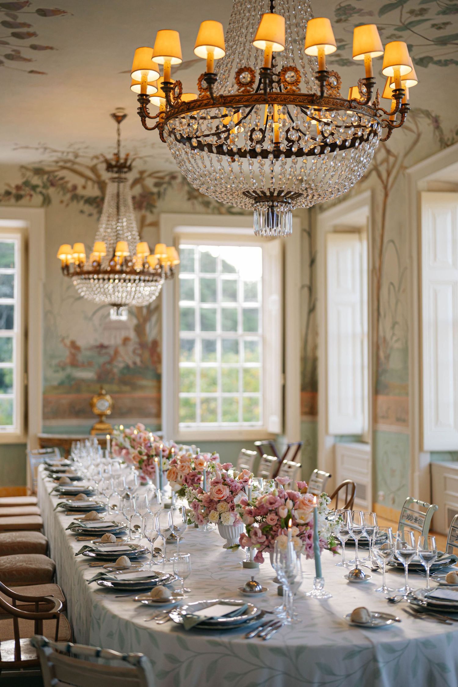 Elegant dining room setup with crystal chandeliers and long table dressed in blue linens for a formal event.
