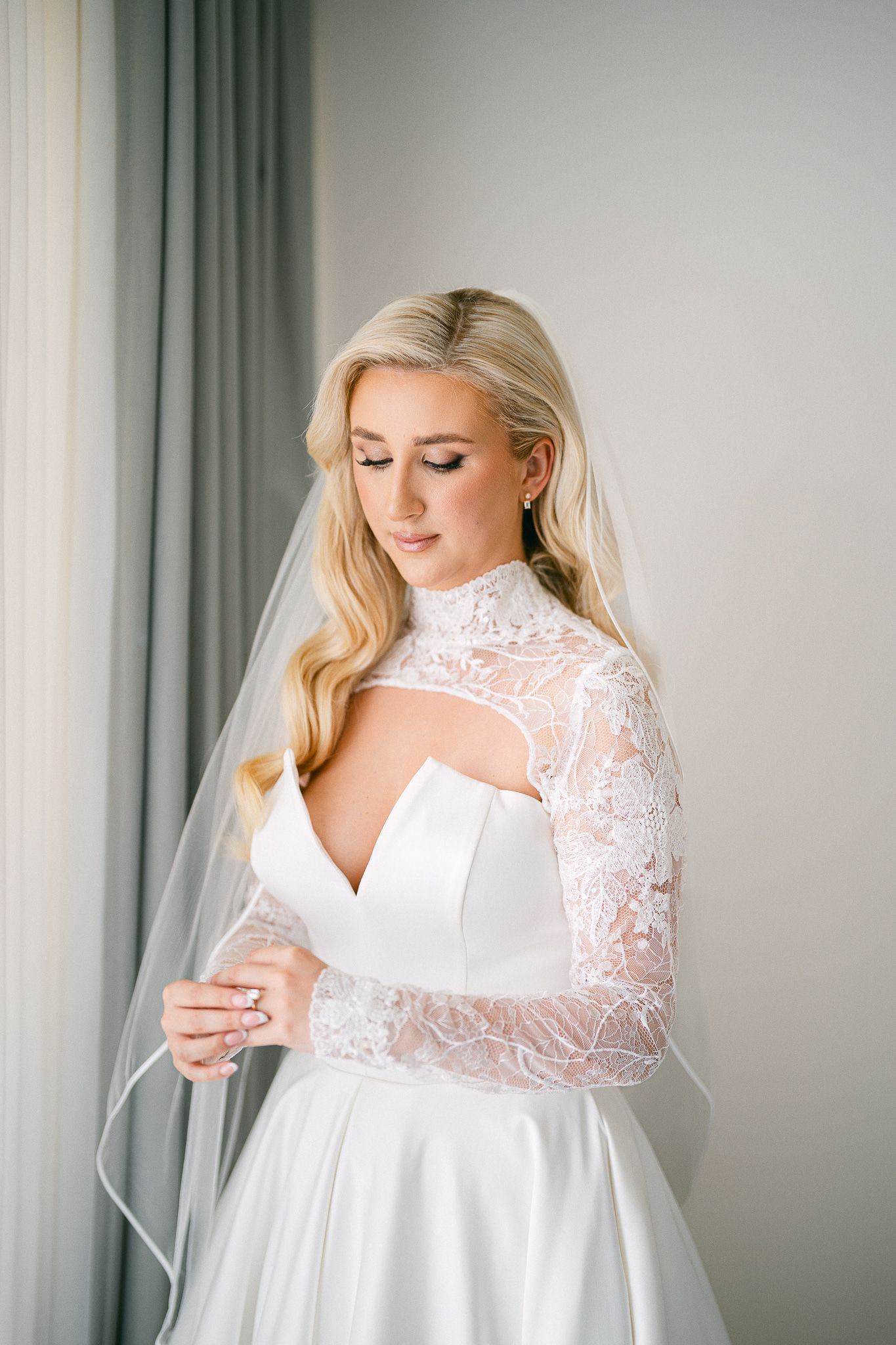 Elegant bridal portrait featuring a modern wedding gown with lace sleeves and plunging neckline design.