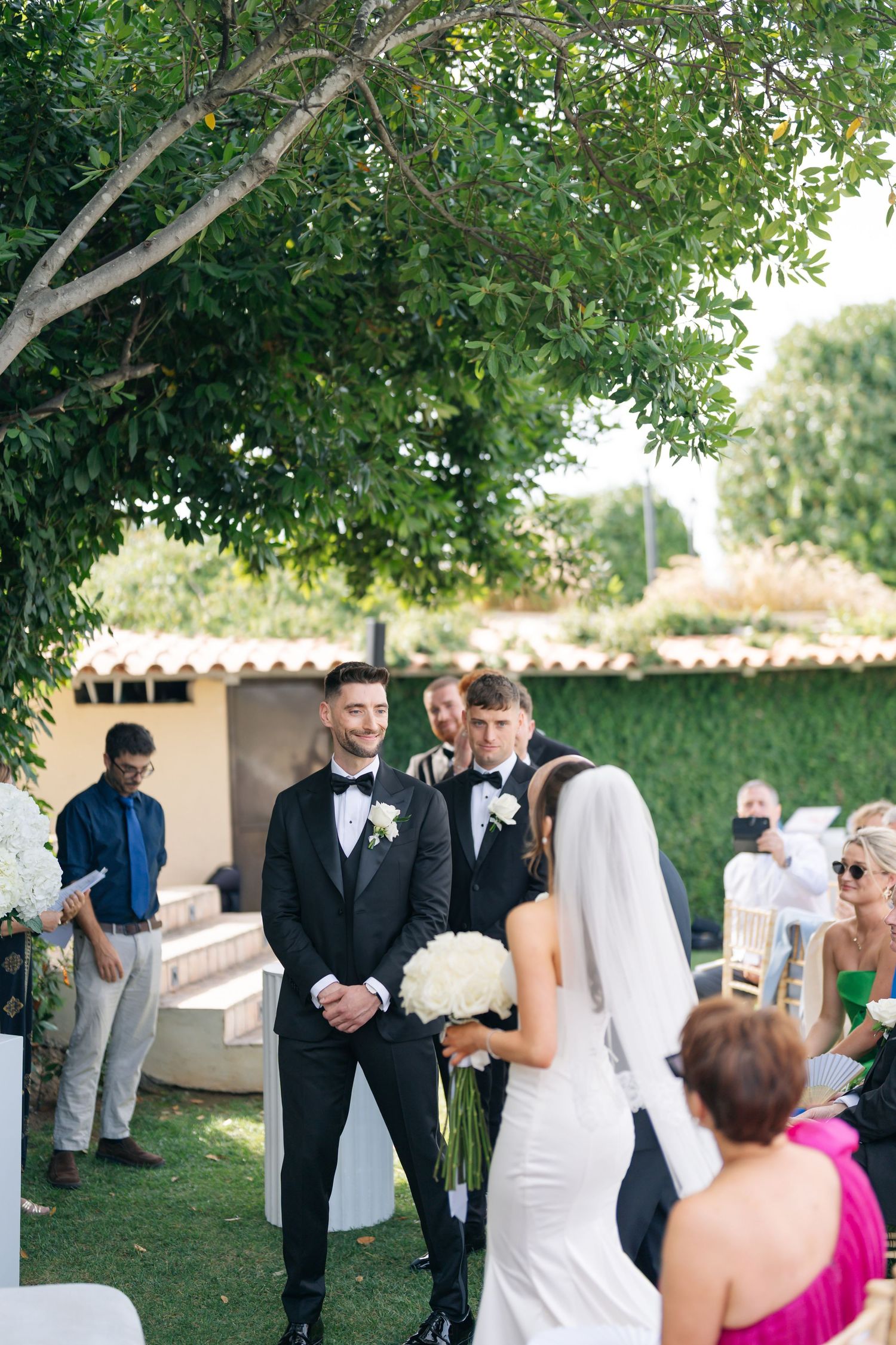 Couple shares a tender moment during their outdoor wedding ceremony with guests looking on.