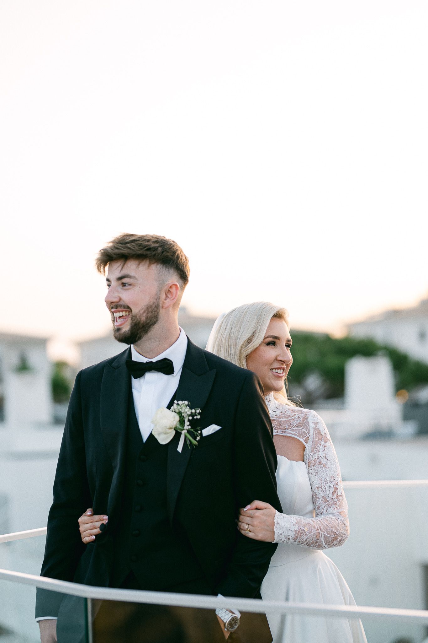 Elegant wedding portraits capture candid interactions between bride and groom on rooftop setting.