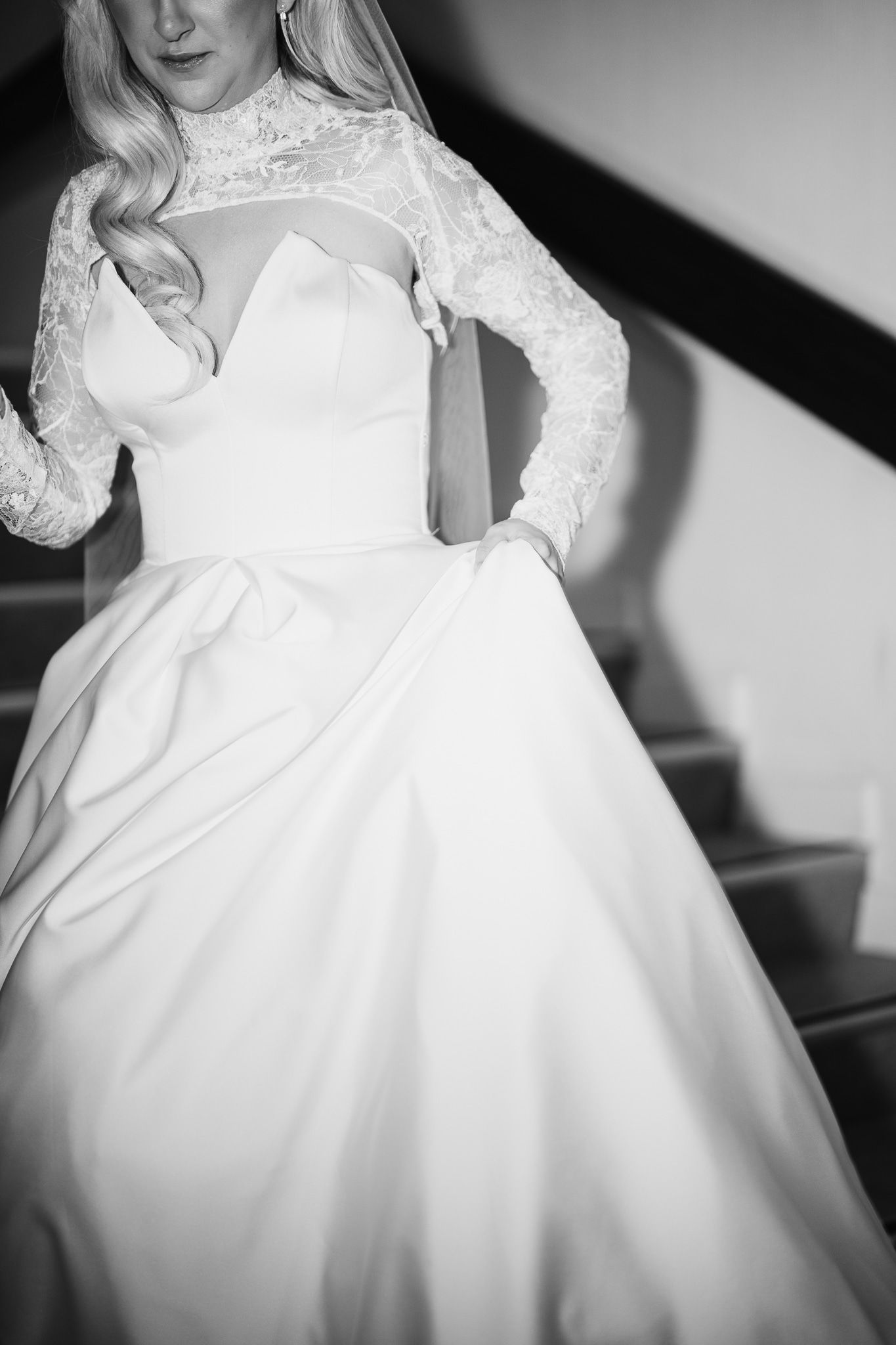 Close-up details of a white wedding dress with lace sleeves in black and white photography.