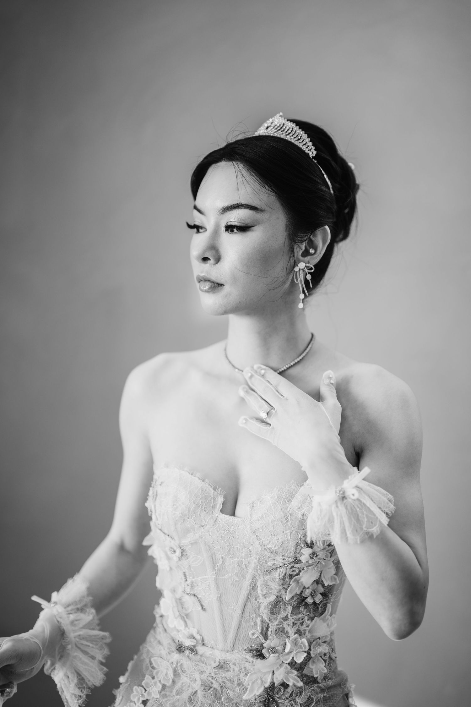 Black and white portrait of a bride in an ornate wedding dress with delicate details.