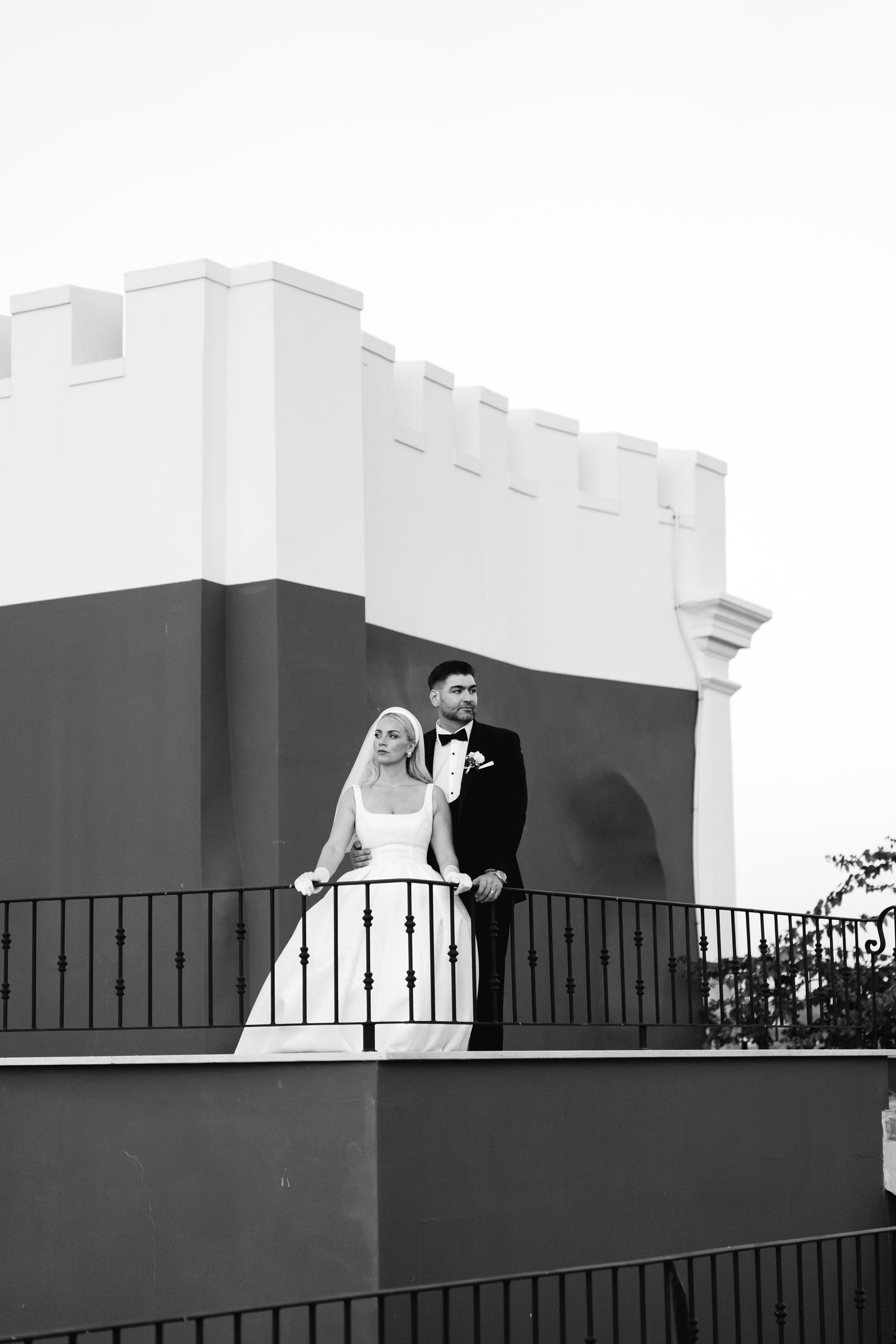 Black and white architectural wedding portrait on a modern balcony with geometric lines.