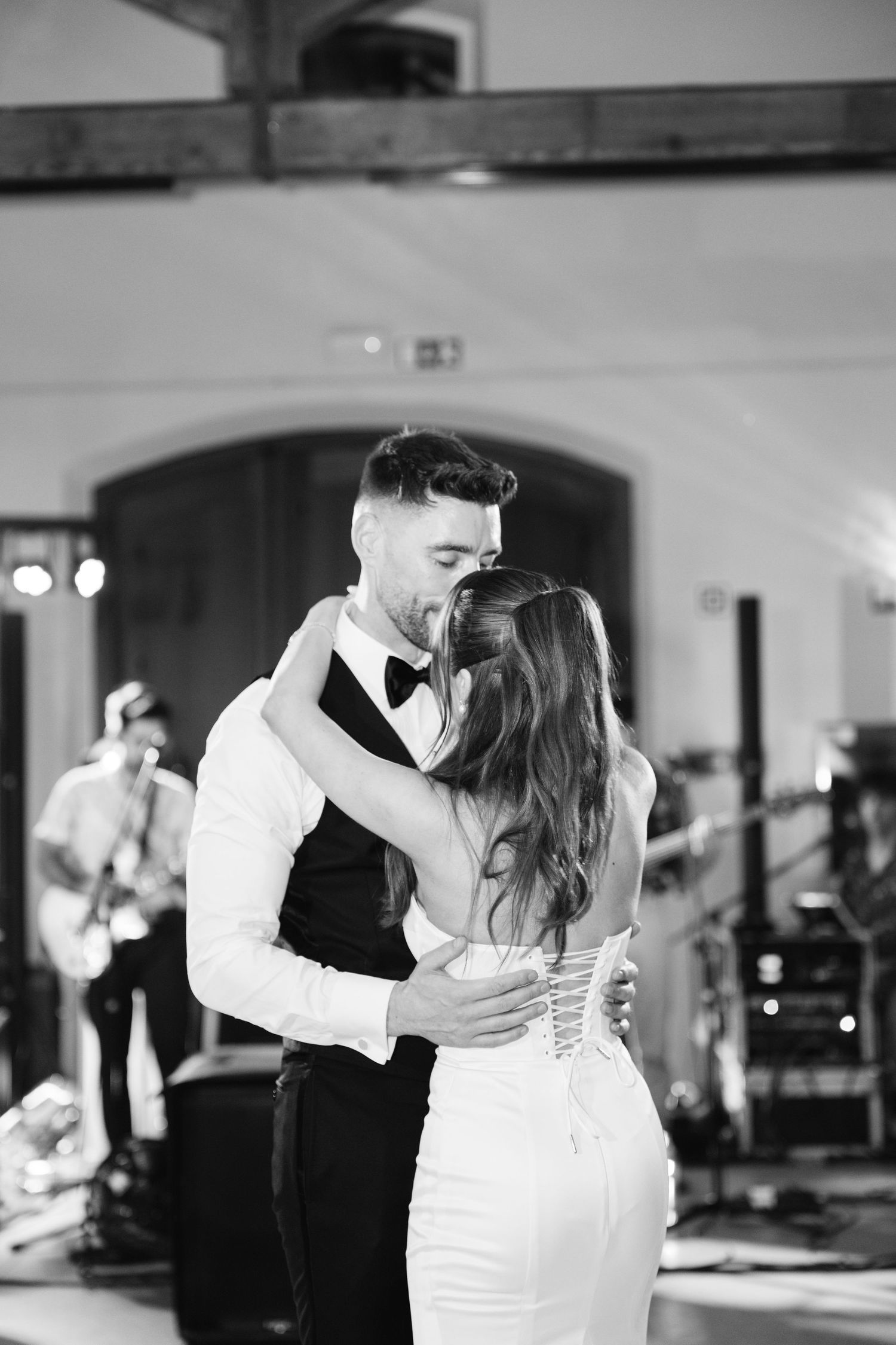 A black and white capture of an intimate wedding dance moment with a band visible behind.