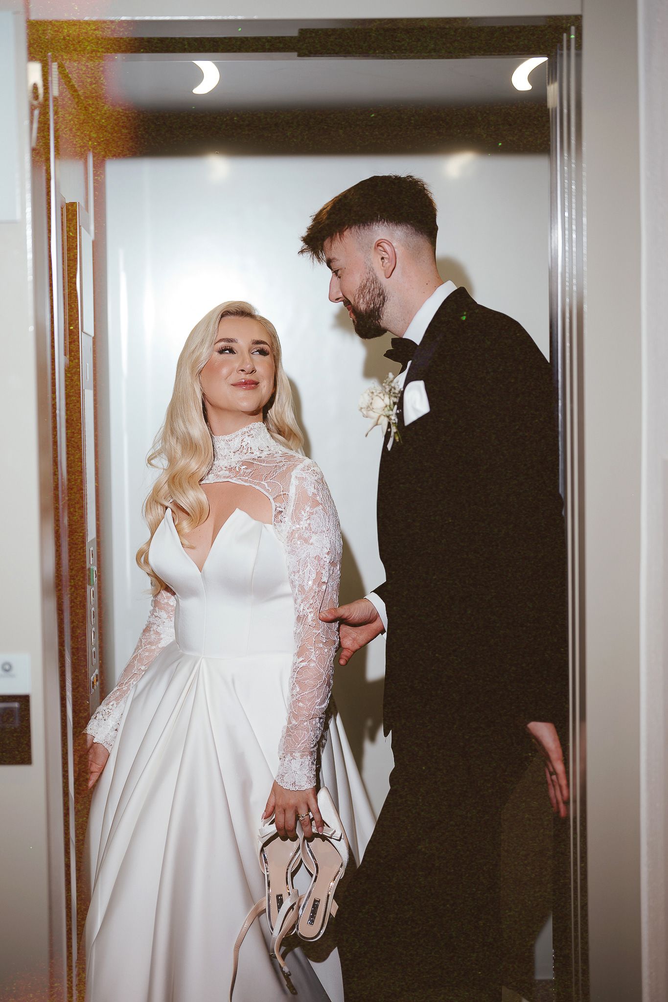 Artistic black and white photo of newlyweds in elevator on wedding day.