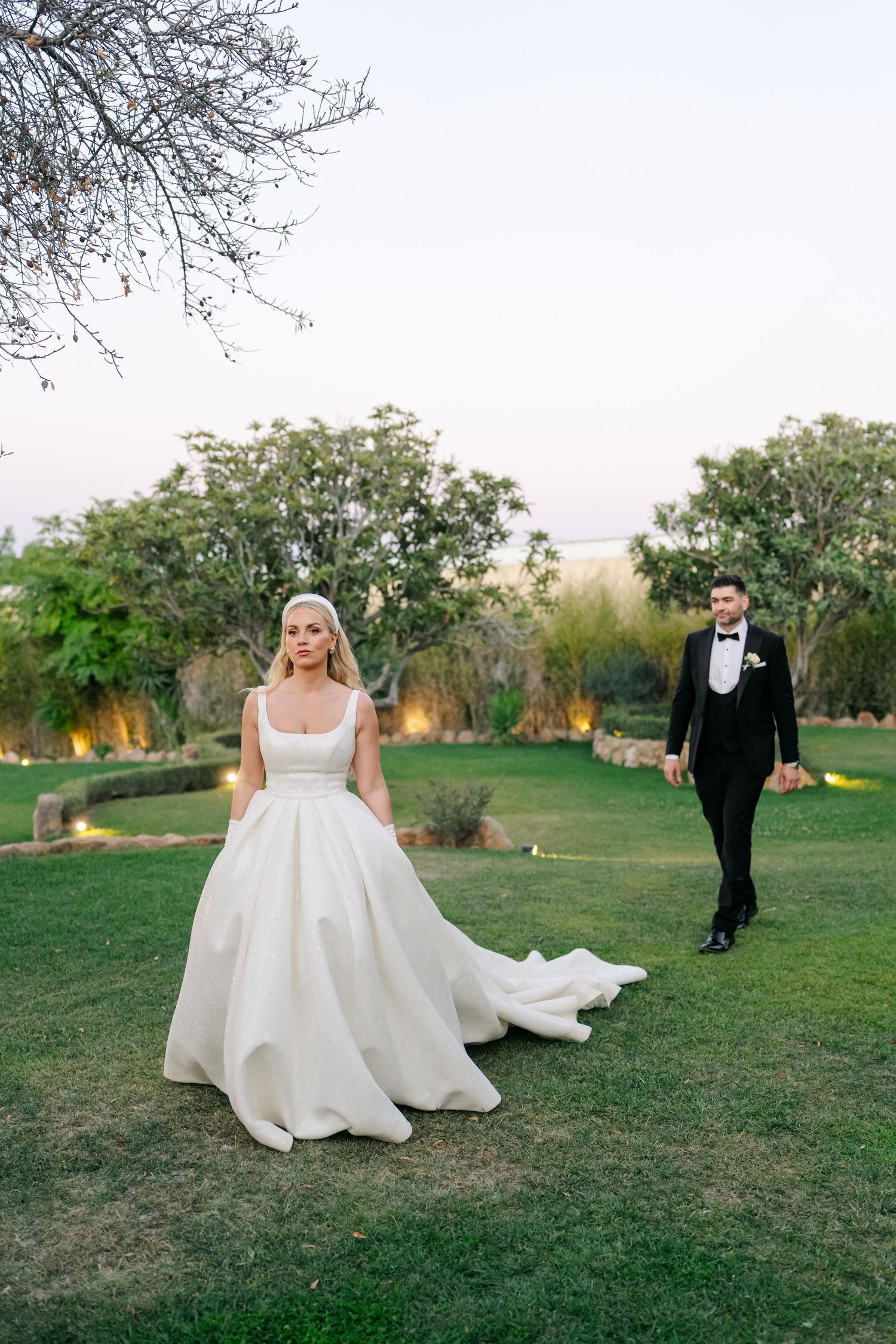 A wedding couple poses in an outdoor garden setting with dramatic lighting.