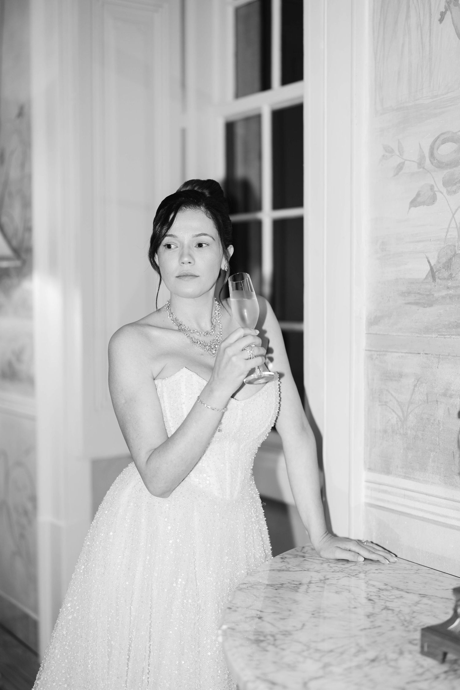 A series of black and white photos showing someone in a white dress sitting by a window in contemplative poses.