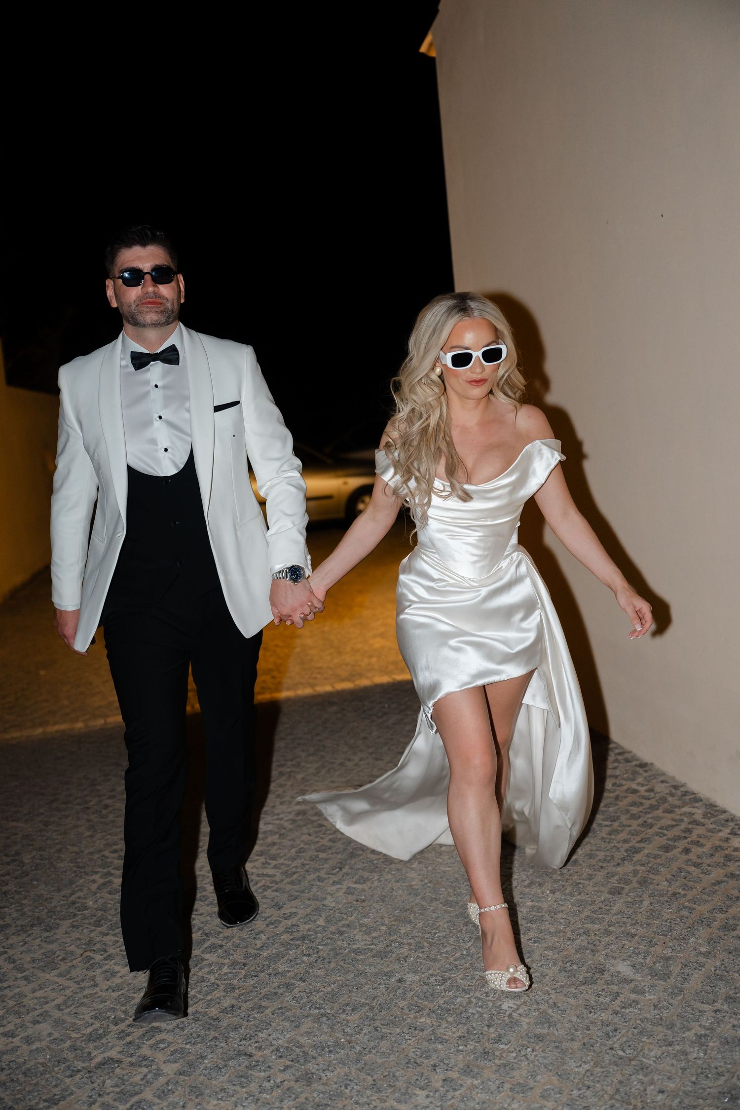 A couple in formal wear dancing on a textured carpet floor.