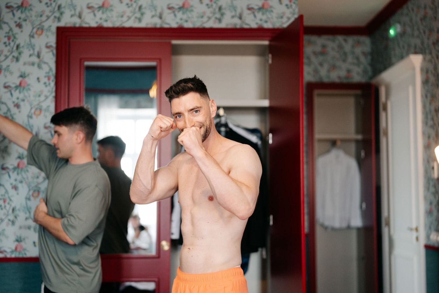 Getting ready scene with floral wallpaper and red accents in the background.