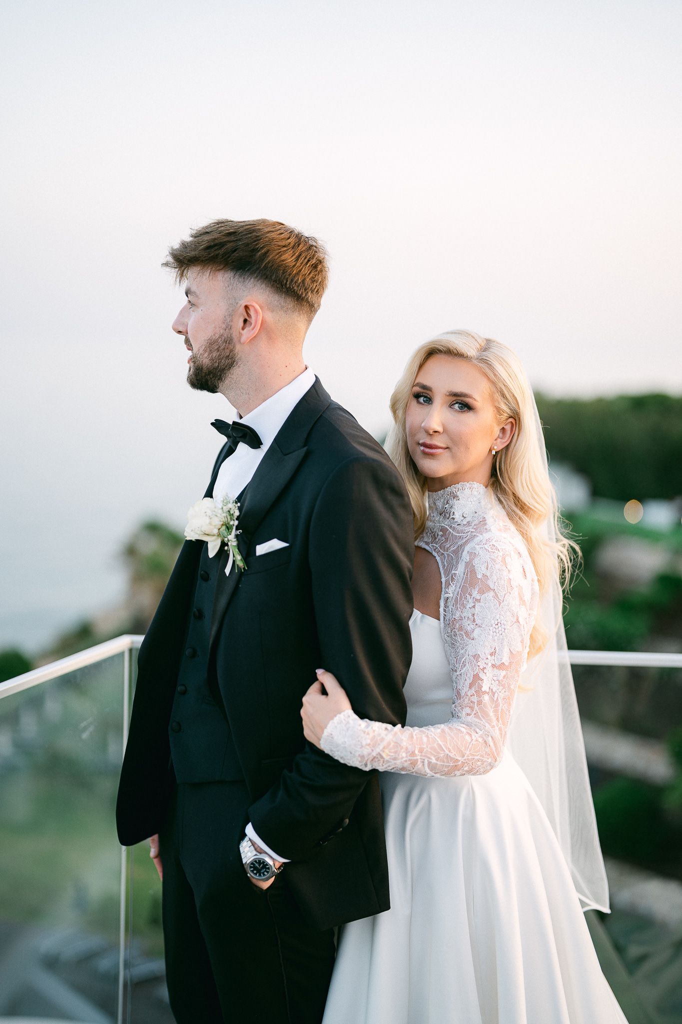 Wedding couple shares romantic moments on outdoor terrace during golden hour photo session.