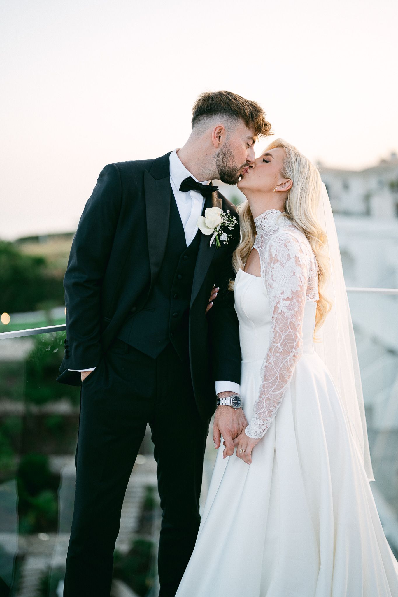 Romantic wedding couple shares intimate kisses in a series of sunset portraits wearing classic black and white attire.