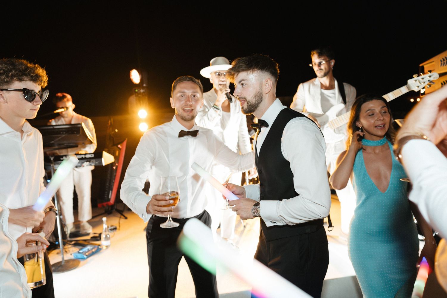 Wedding reception guests dancing and socializing under outdoor lighting.