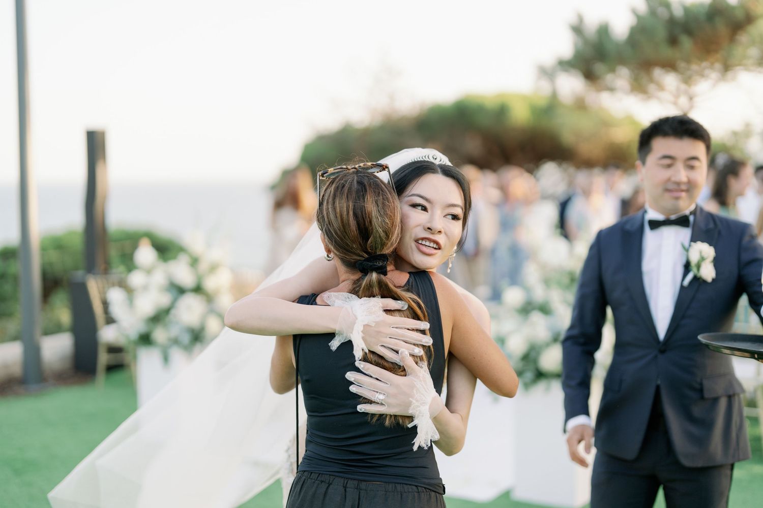 Wedding guests share warm embraces during an outdoor celebration.