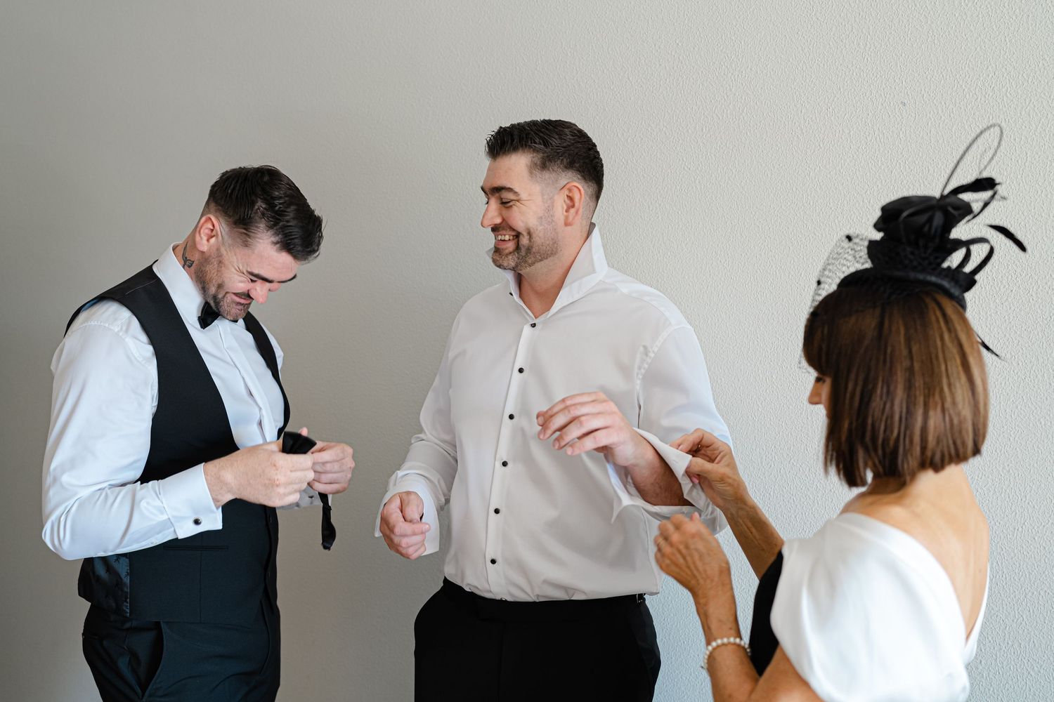 Wedding party members laughing and interacting during formal event preparations.