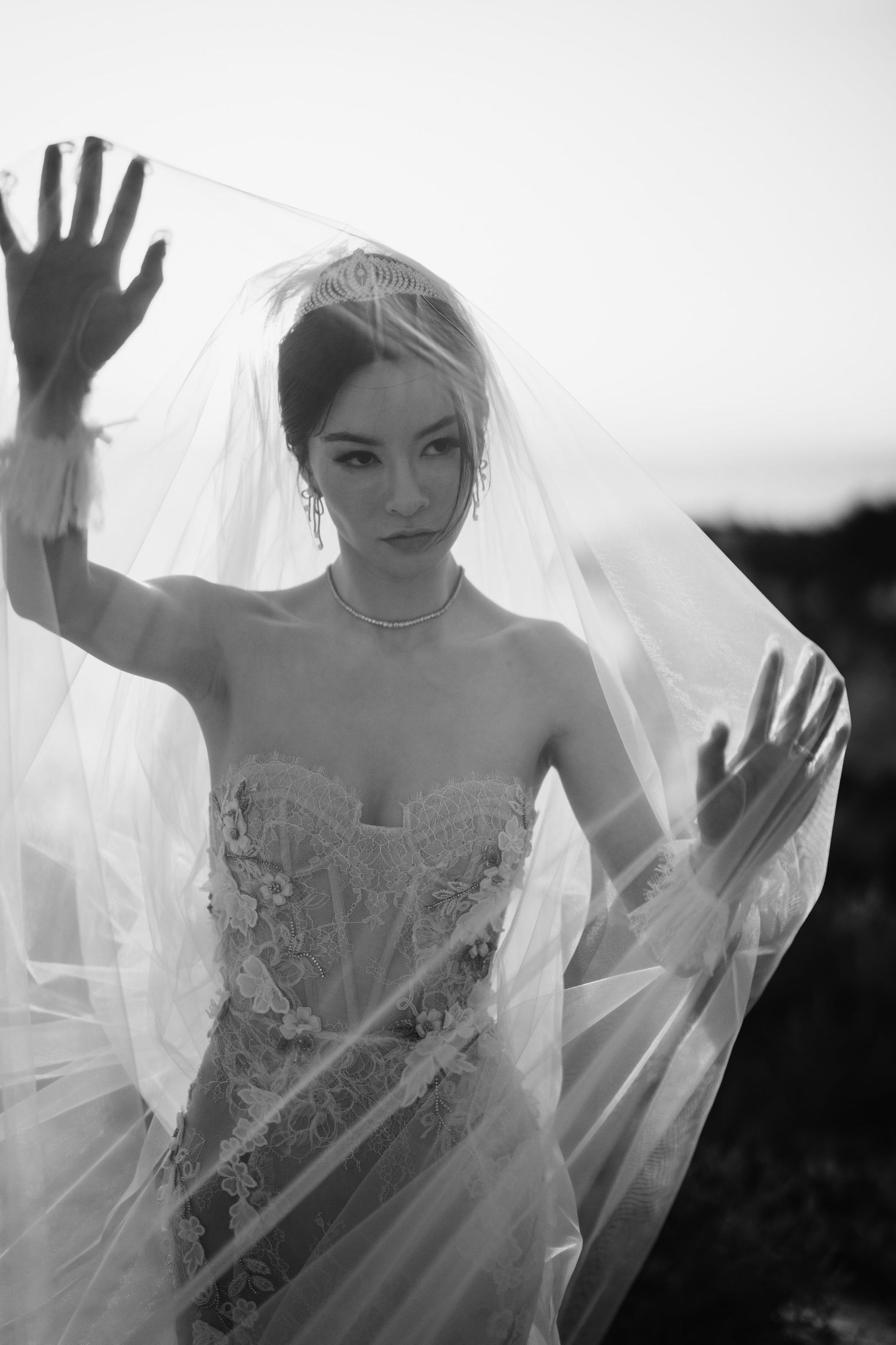 Artistic black and white bridal portrait with flowing veil creating dramatic effect.
