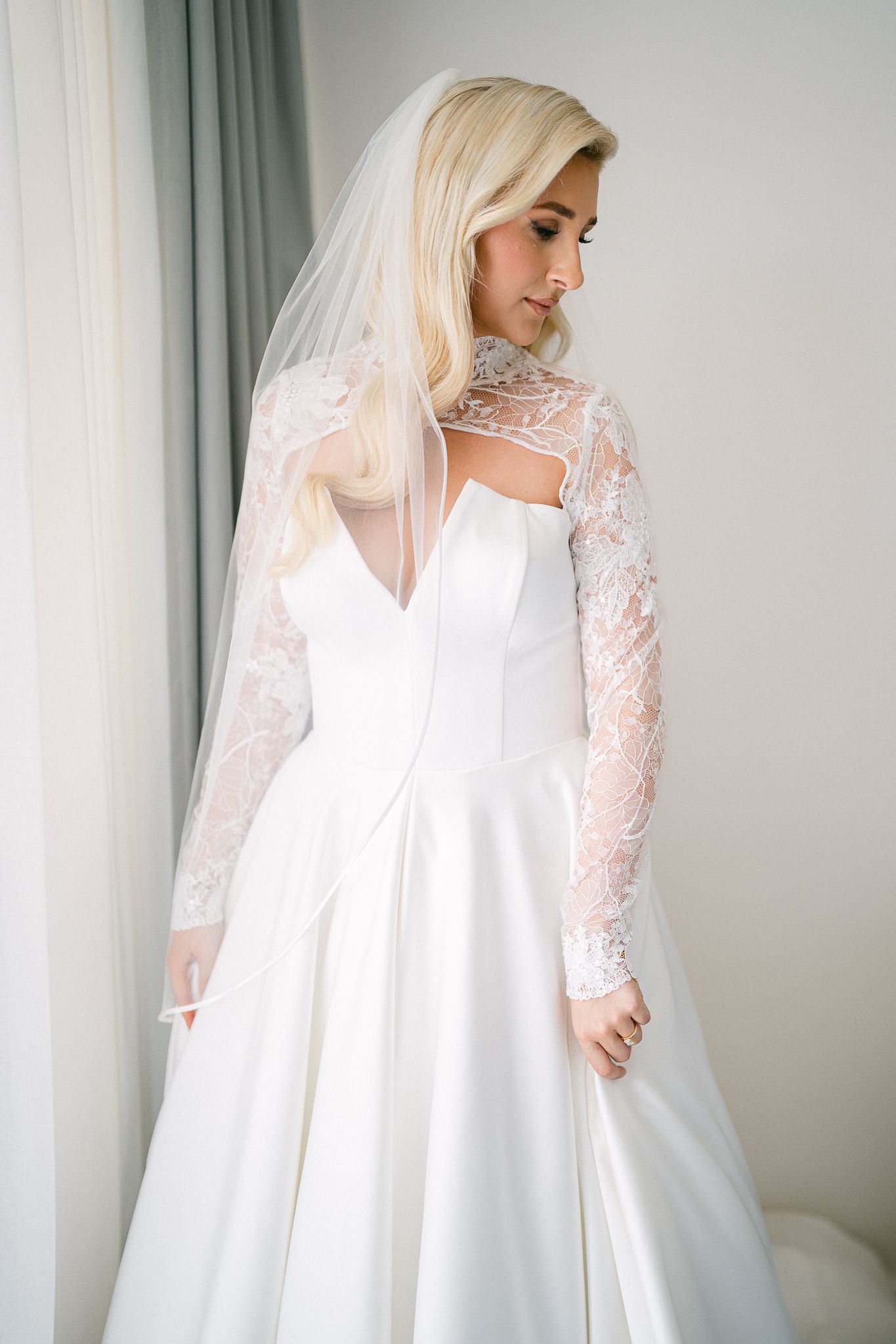 Side view of wedding dress featuring structured bodice, full skirt and delicate lace overlay sleeves.