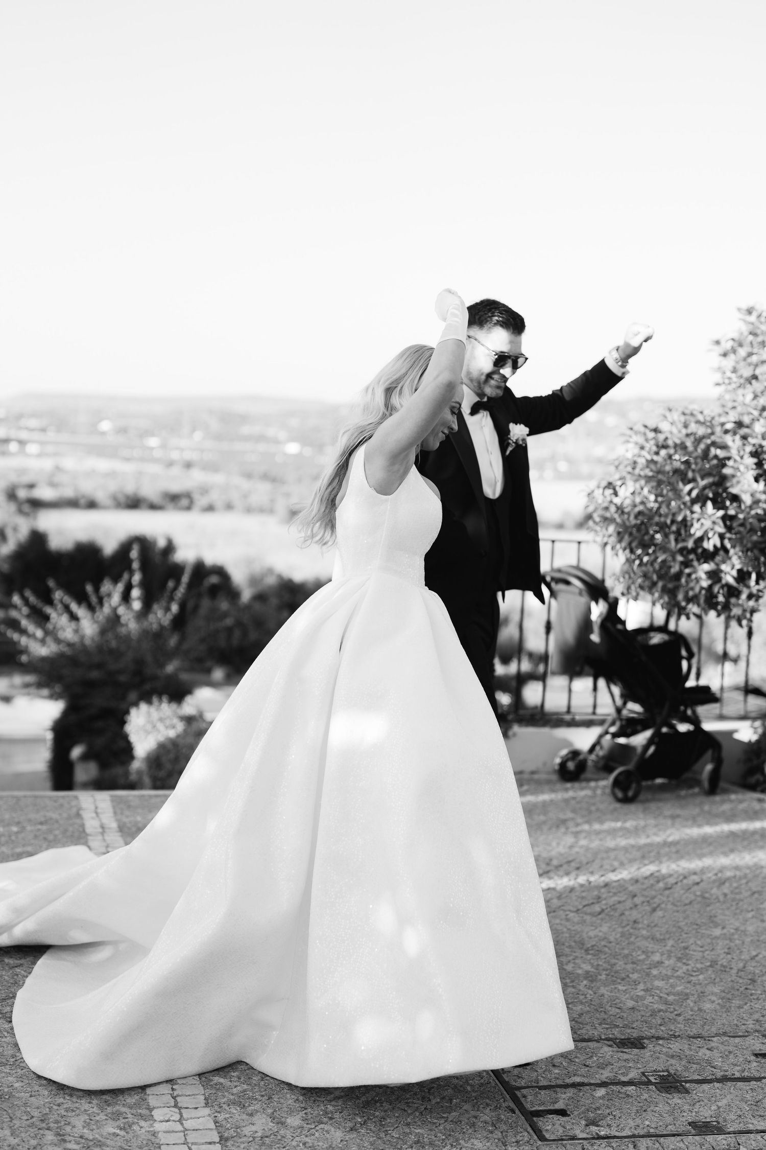 Black and white wedding photo of a couple dancing on an outdoor terrace.