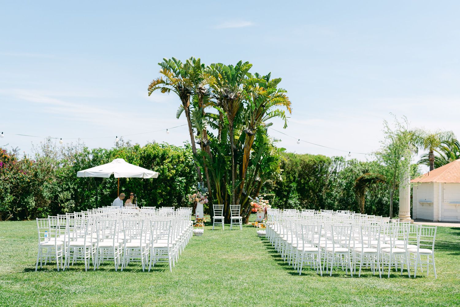 White chairs arranged in rows on a grassy lawn for an outdoor wedding ceremony.