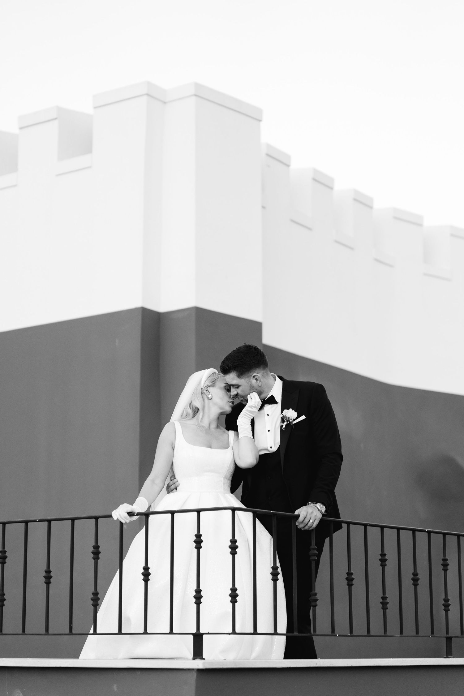 Dramatic black and white wedding portrait series on a modern architectural balcony.