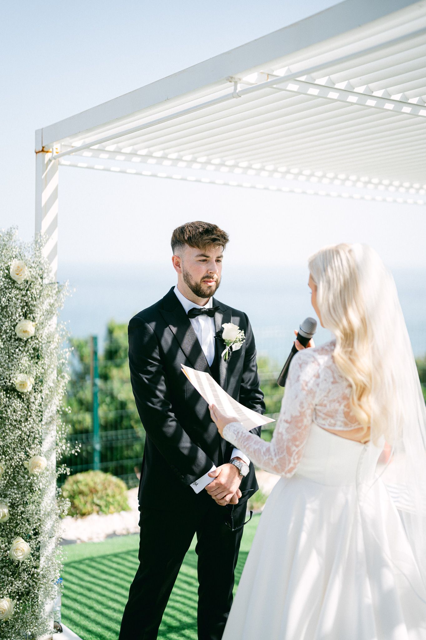 Candid wedding moments captured under white pergola with garden backdrop.