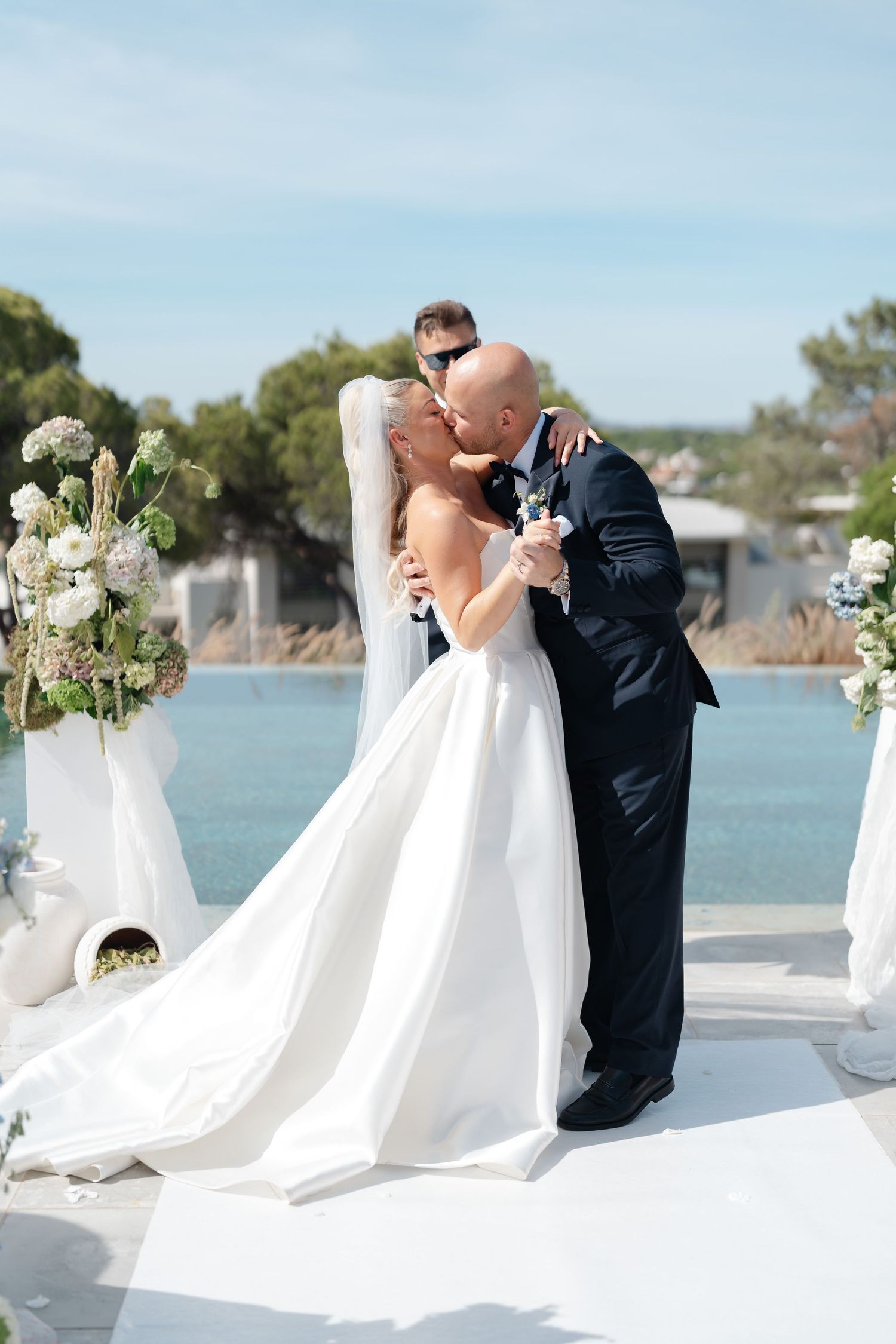 Wedding ceremony setup with white draping and floral arrangements along waterfront venue.