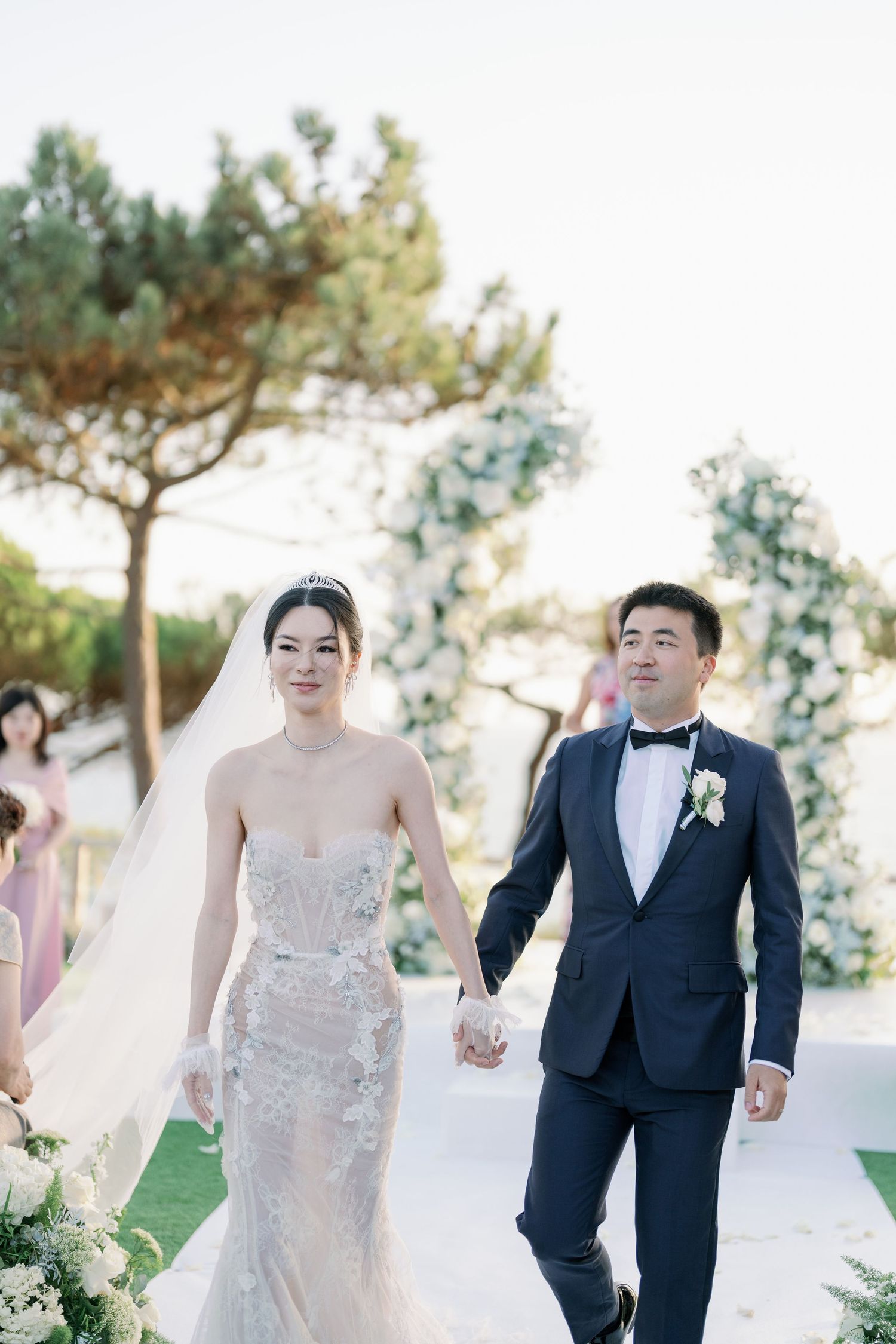 Newlyweds walking down aisle together at outdoor garden wedding ceremony.