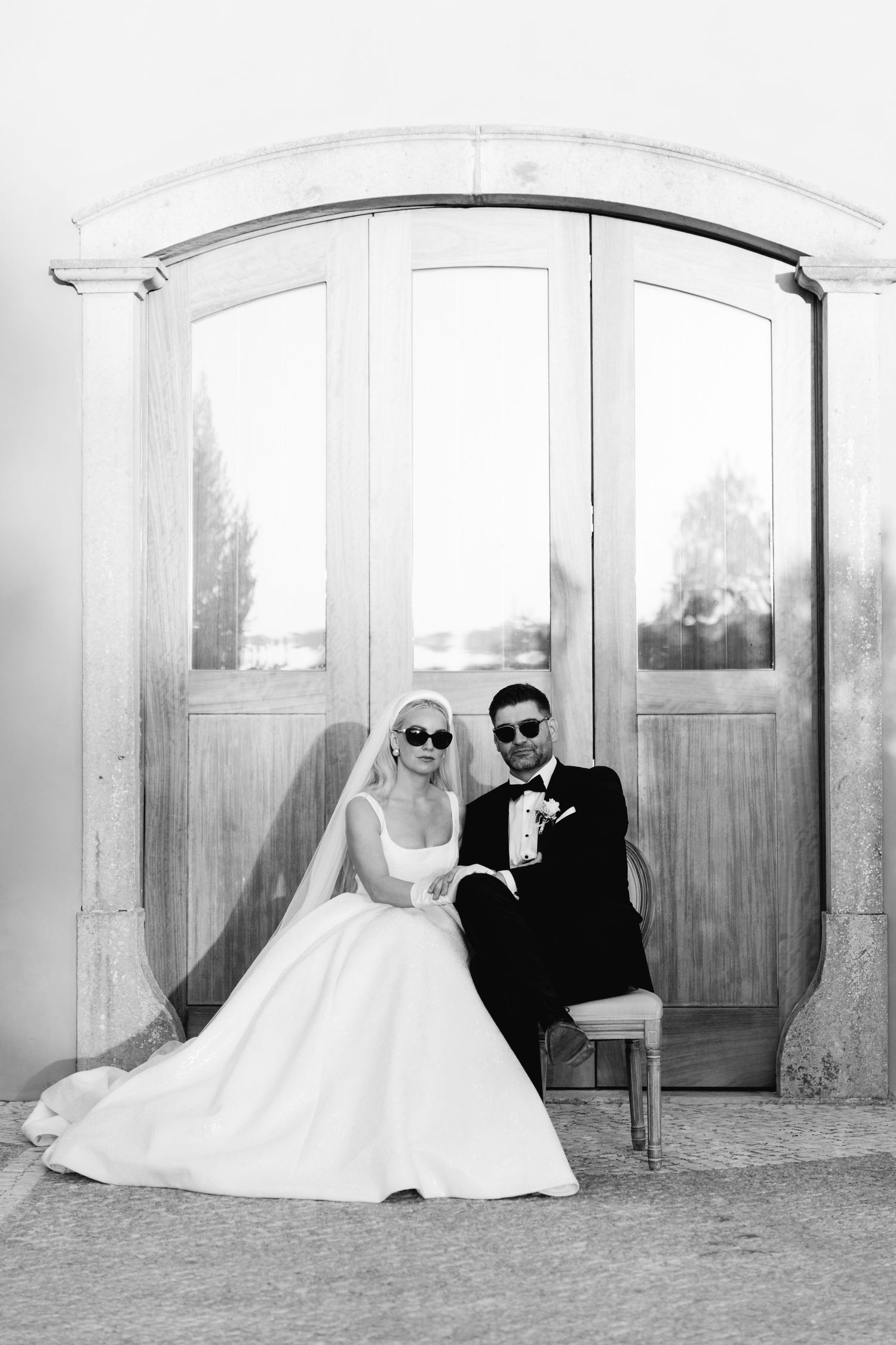 Black and white wedding portraits taken against an elegant arched white wall backdrop.