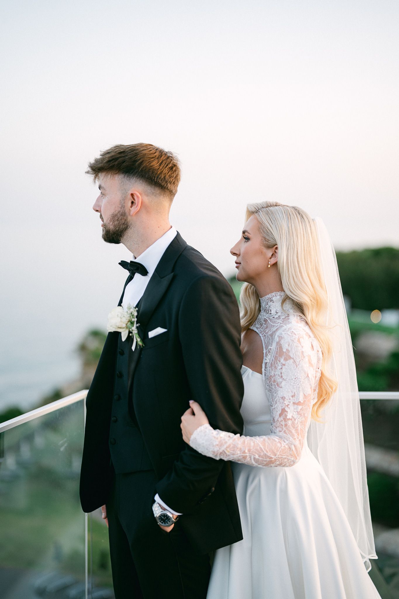 Candid wedding photography captures playful moments between bride and groom on balcony.