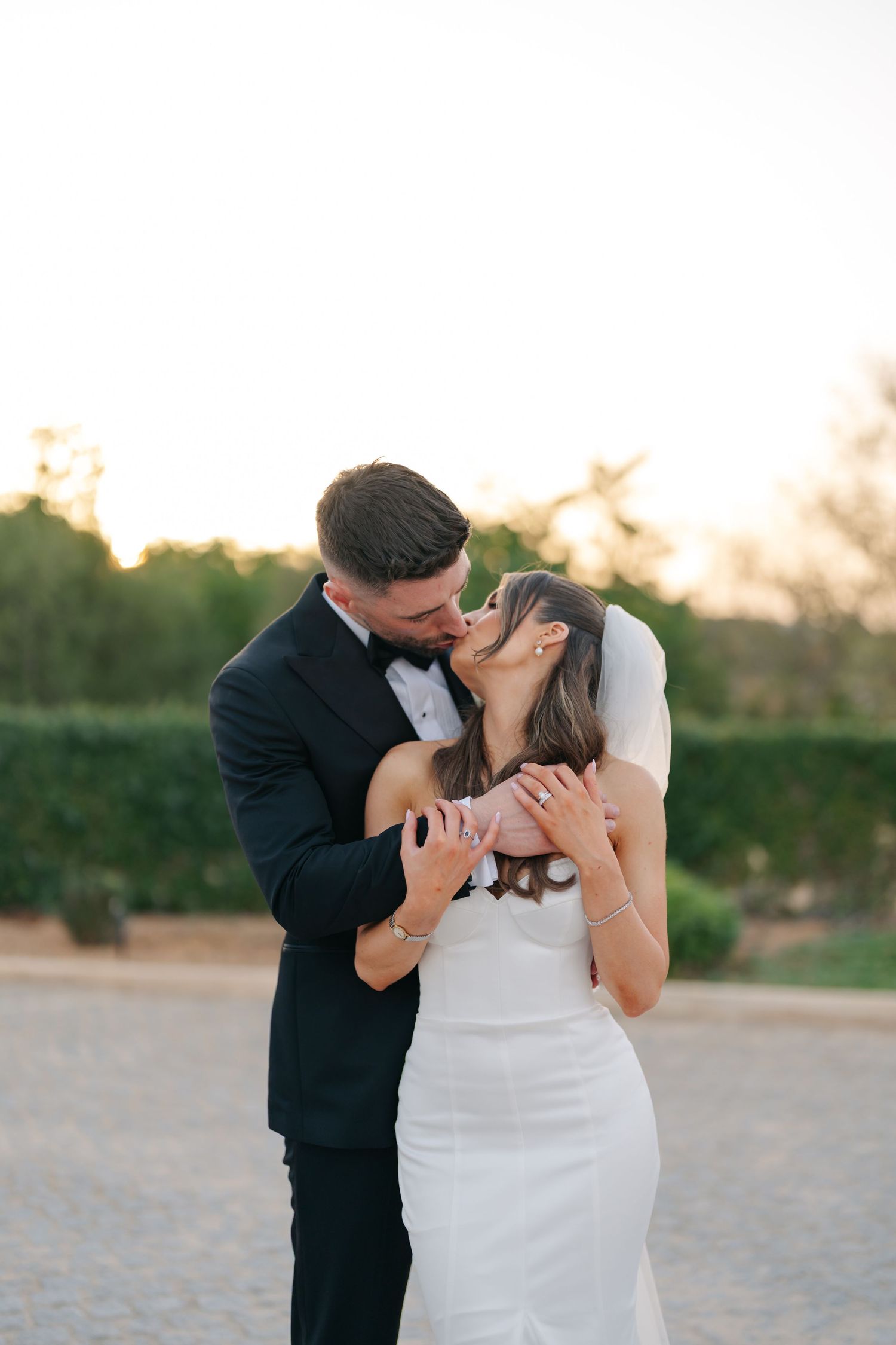 A tender moment between newlyweds embracing during sunset at their wedding.