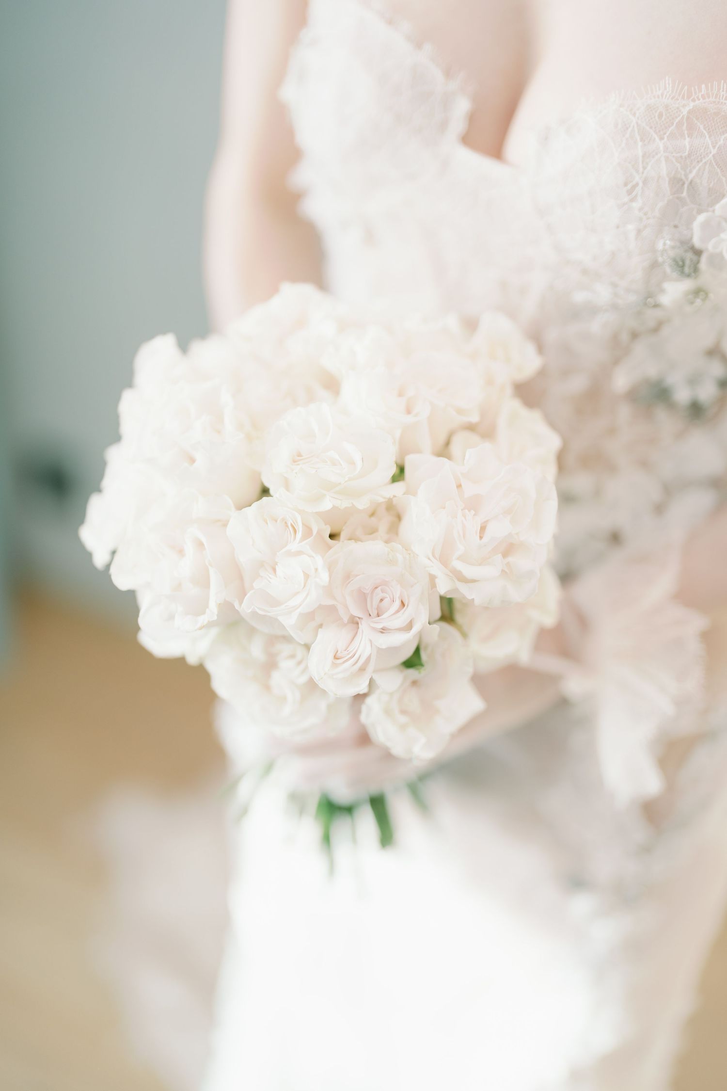 Elegant white rose bridal bouquet with delicate lace details in soft focus.