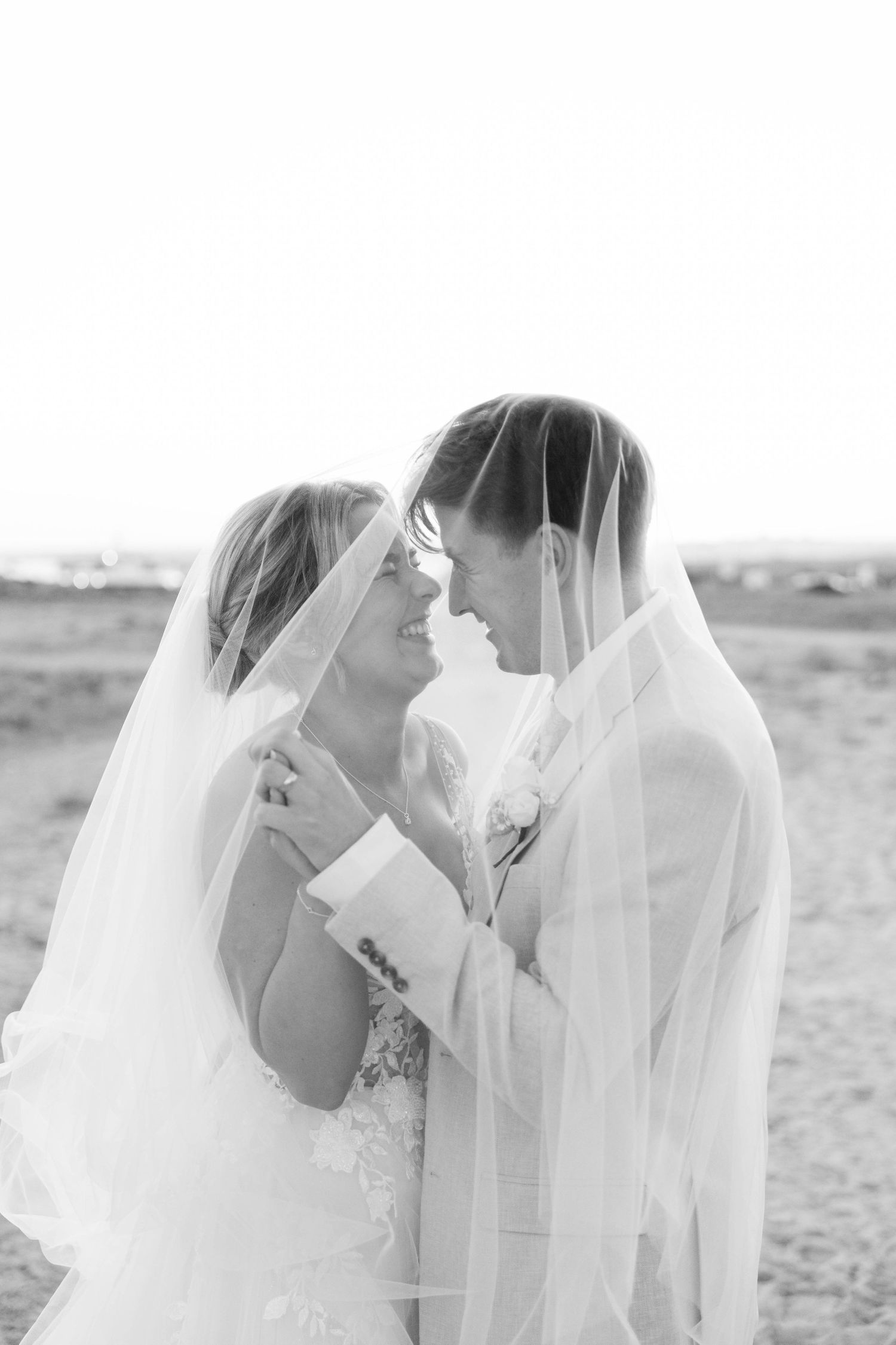 A romantic black and white wedding photo series showing intimate moments between newlyweds with flowing veils.