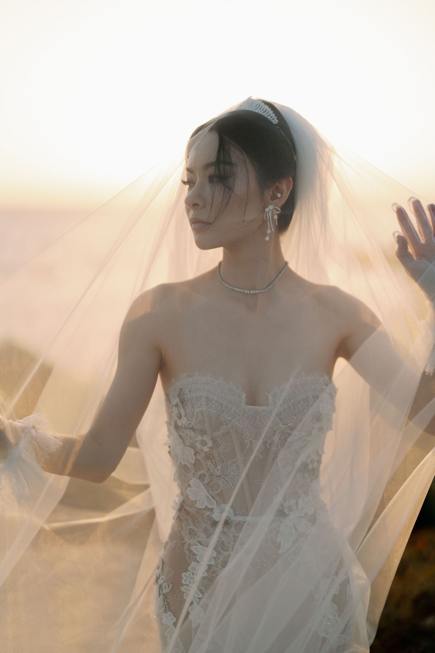 Ethereal bridal portraits with flowing veil captured in warm sunset light.