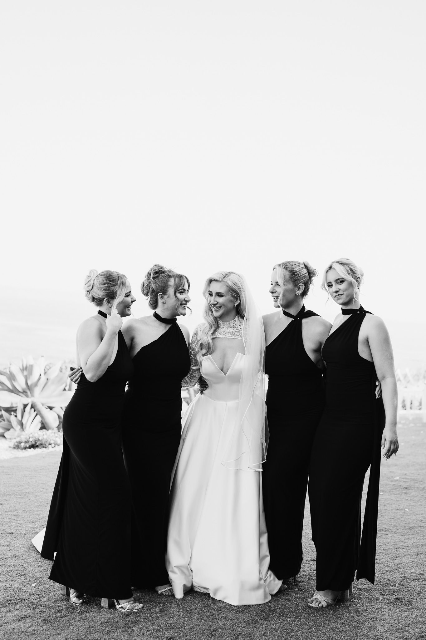 Wedding party lined up in classic black and white attire for formal outdoor portrait.