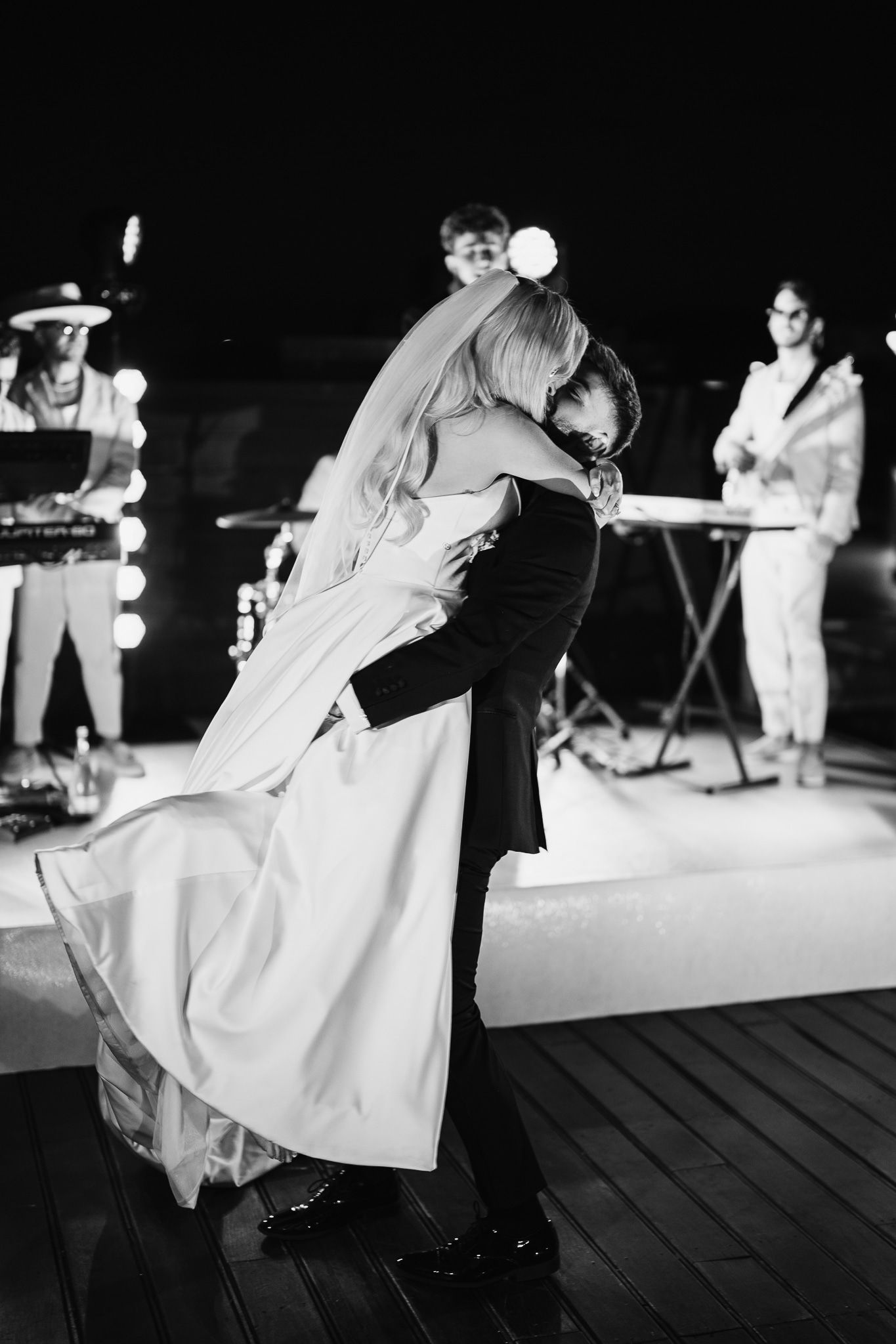 Wedding couple dancing on a wooden deck at night.